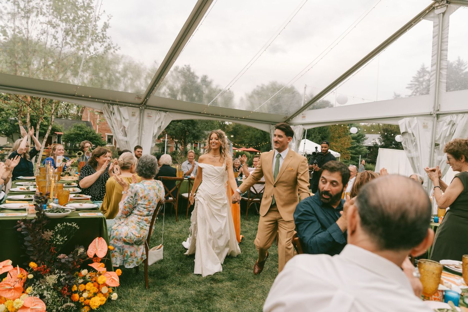Guests dancing and celebrating at an outdoor wedding reception under a white tent canopy.