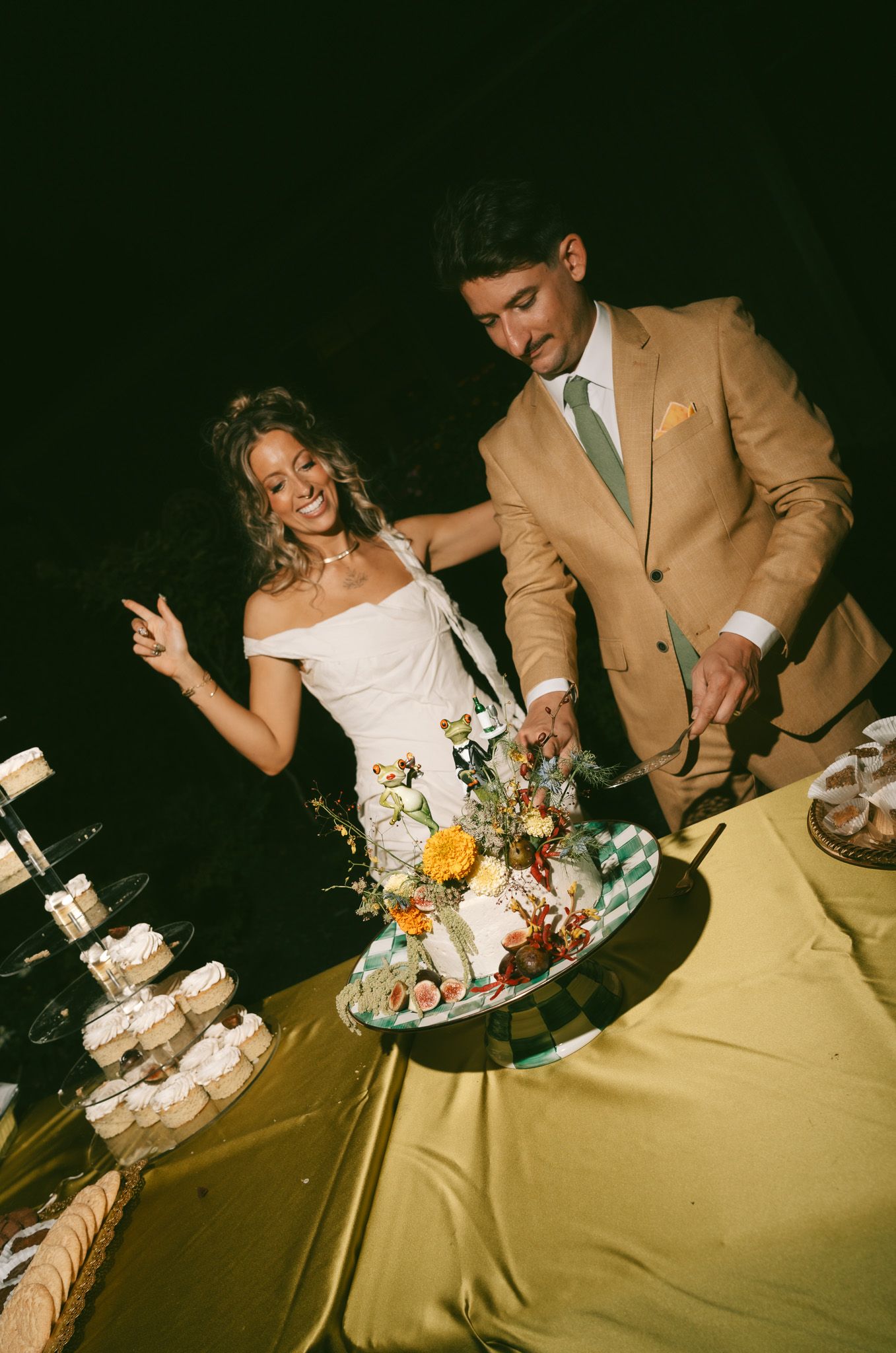 A couple in wedding attire playfully smashes and feeds each other wedding cake during their reception celebration.