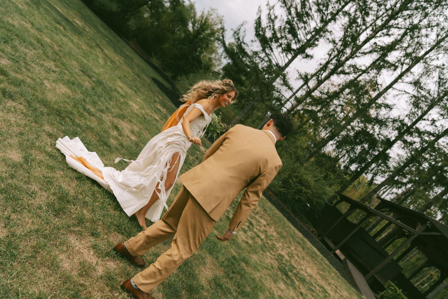 A couple in formal attire dances gracefully in an outdoor garden setting during a wedding celebration.