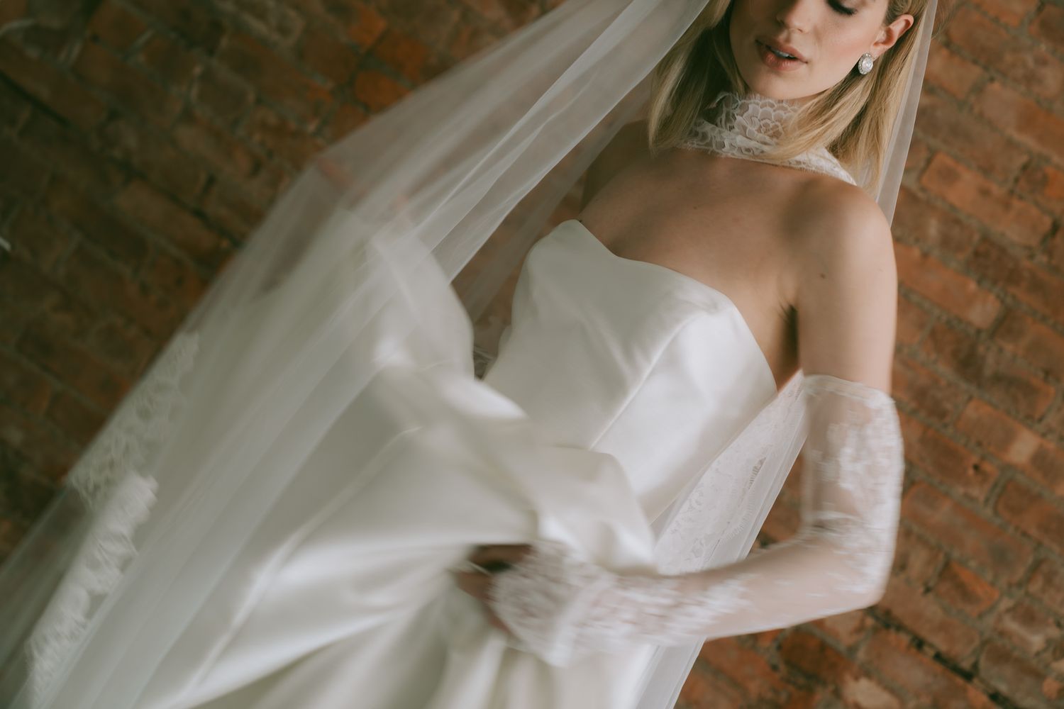 Wedding dress details with sweetheart neckline and delicate lace elements against brick wall in NYC