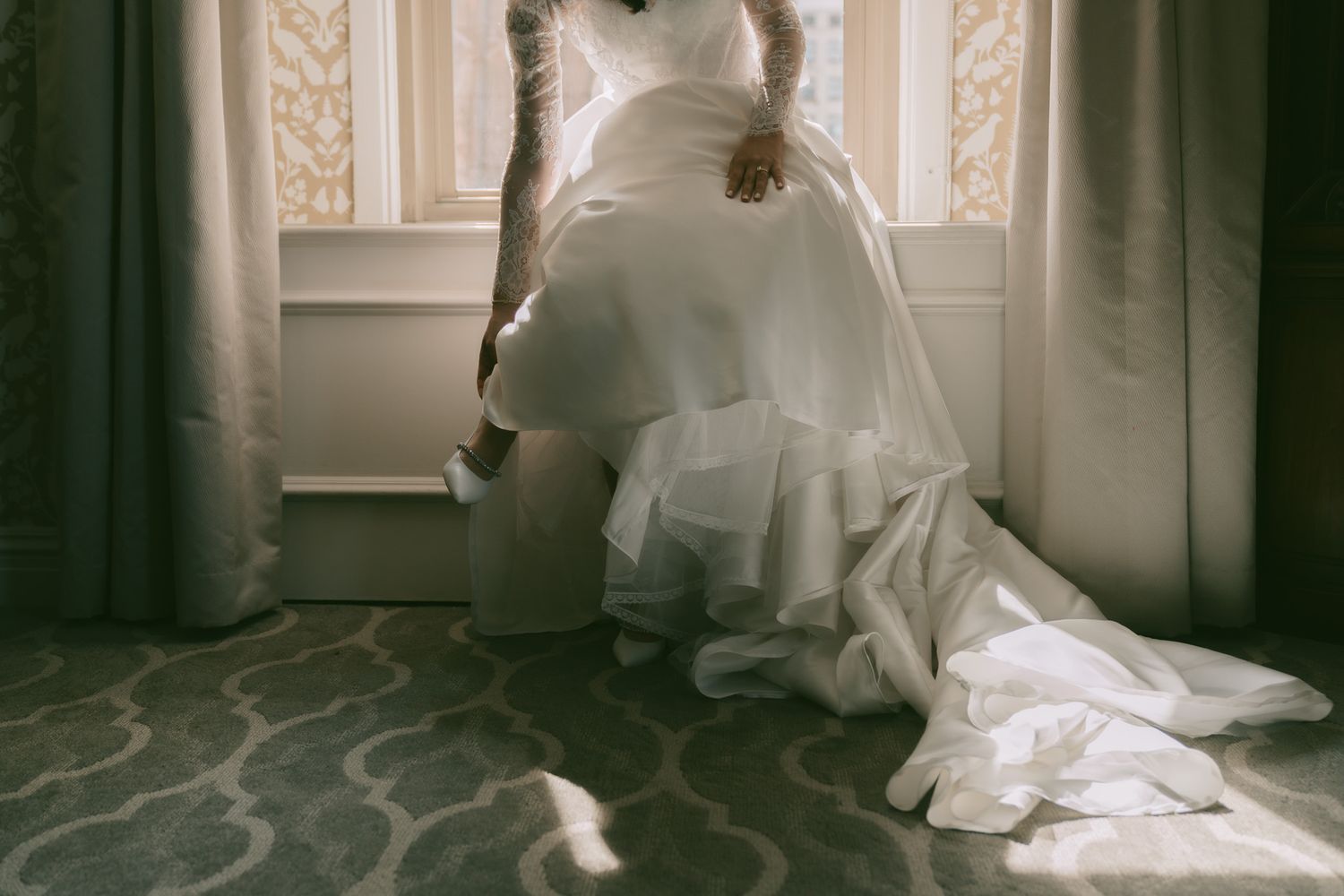 Bride in white wedding gown sits gracefully on patterned carpet in downtown pittsburgh, pa..