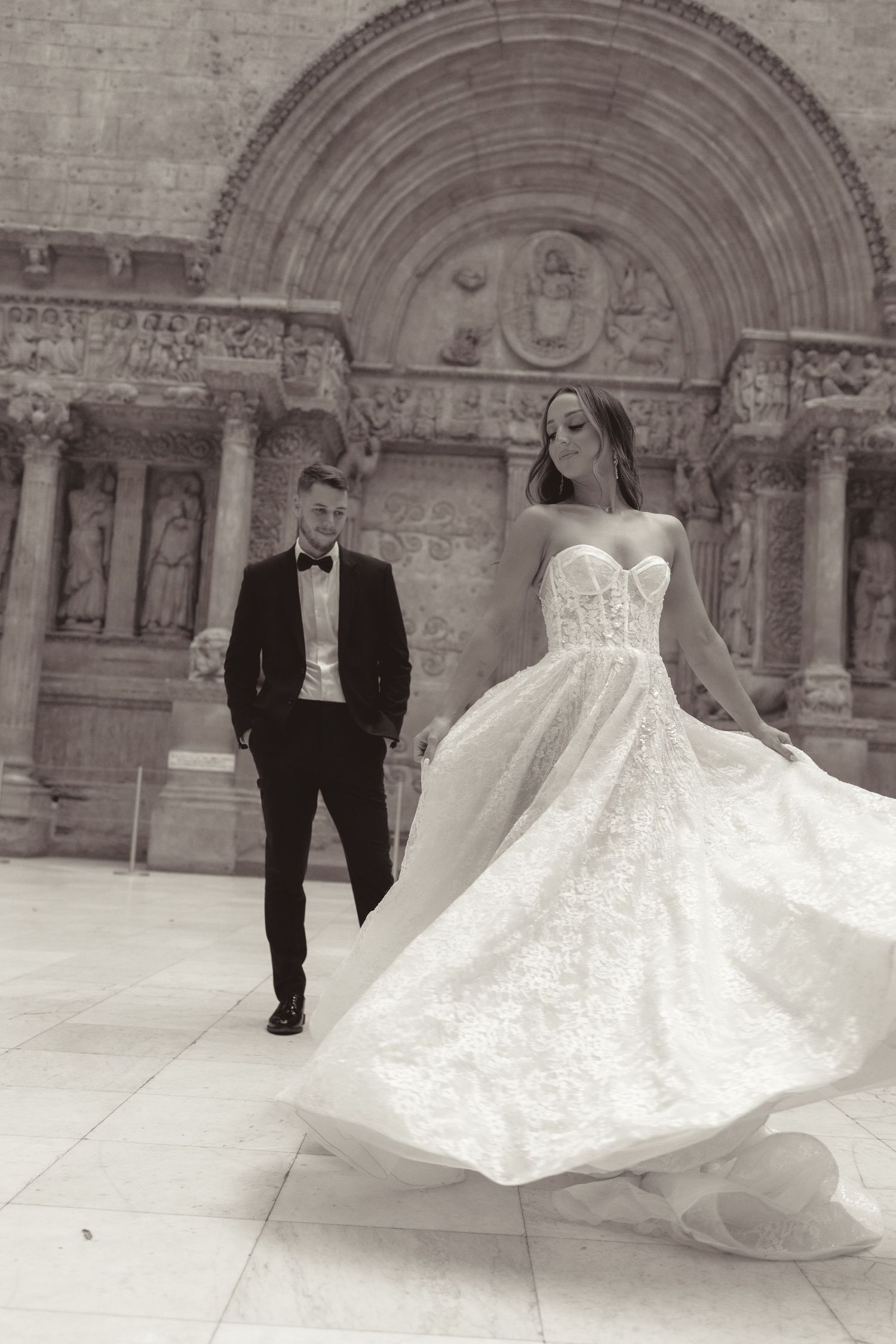 A wedding couple twirls on a stone courtyard in a series of black and white photos showing the bride's dress in motion.