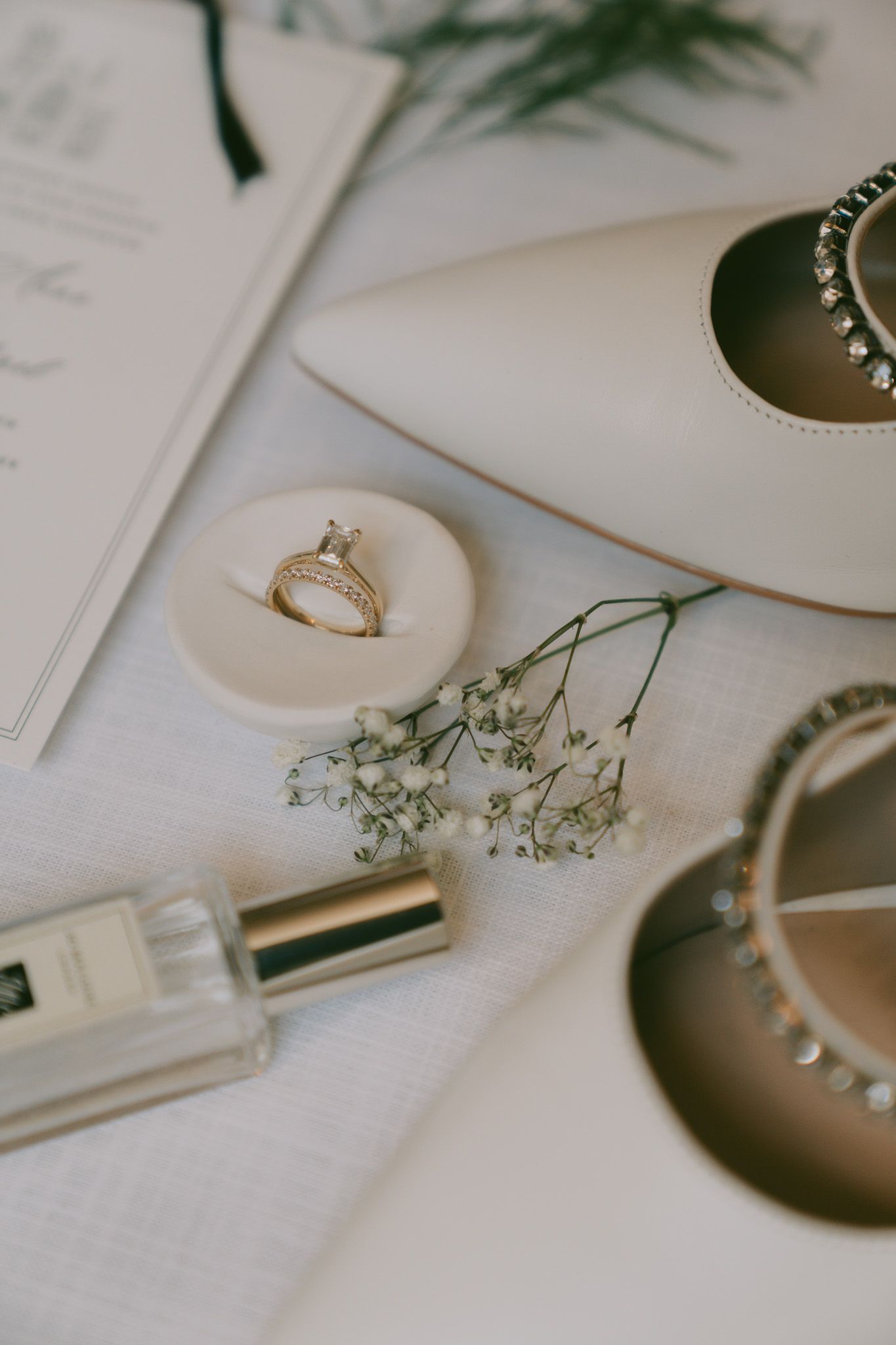 Wedding detail shot of rings and delicate baby's breath flowers on white paper.