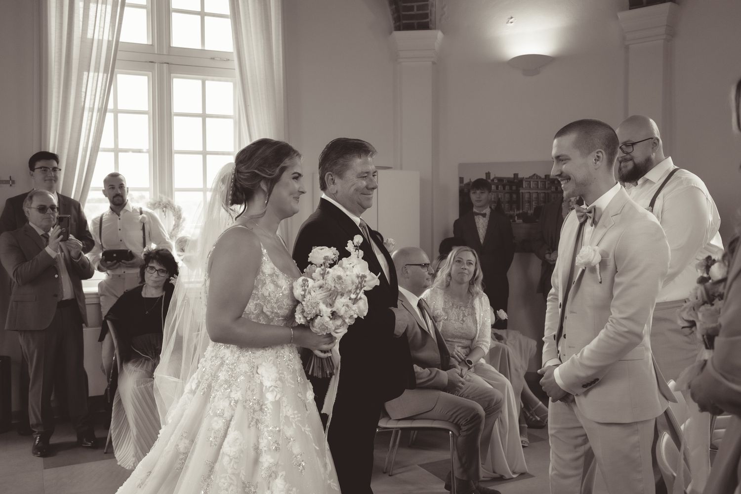 Indoor wedding ceremony with guests watching the couple exchange vows in a bright room in Germany.