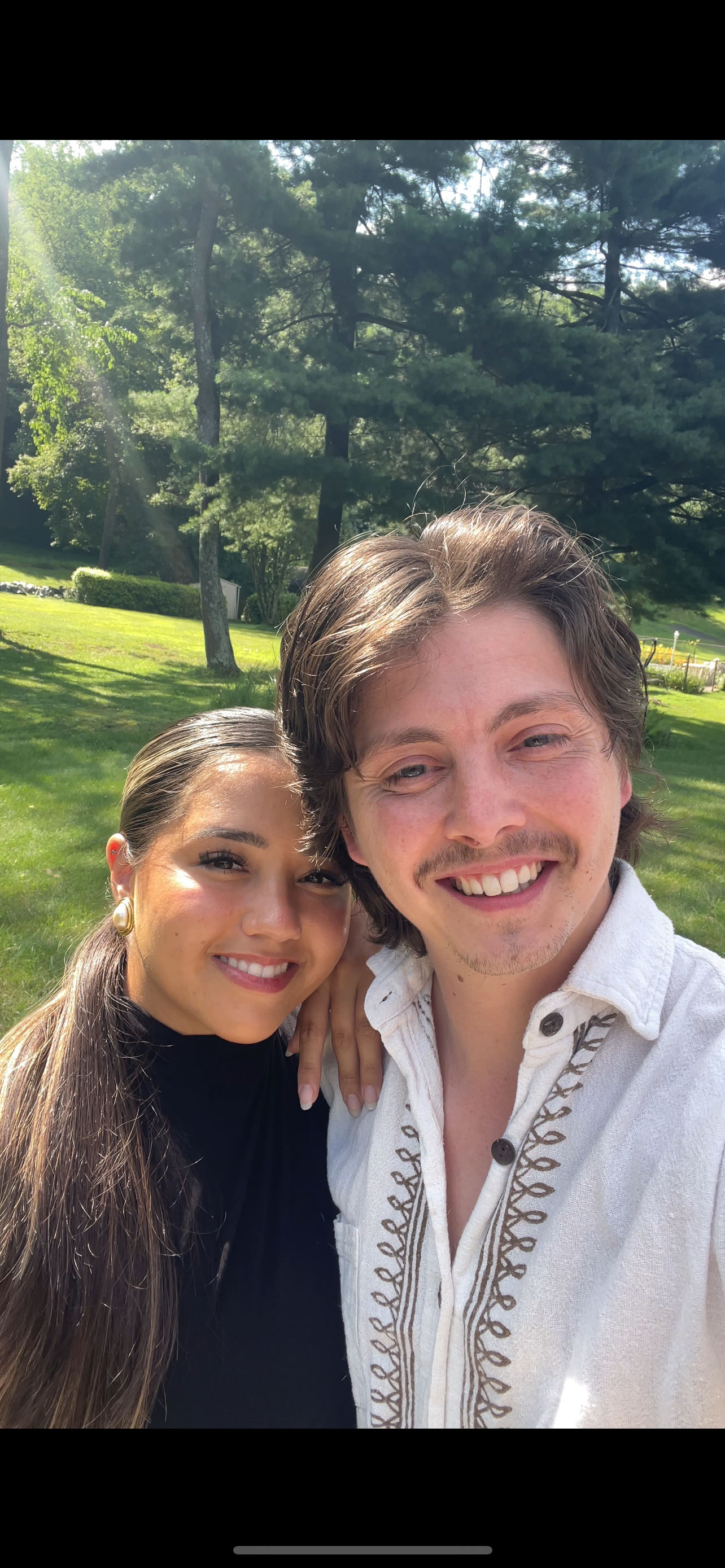 Casual outdoor portrait of couple smiling in sunny garden setting.
