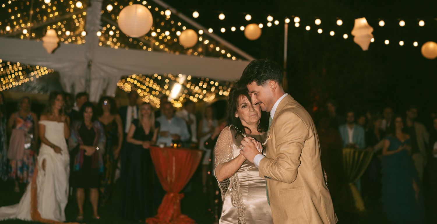 Outdoor evening wedding reception with string lights and paper lanterns creating a warm romantic atmosphere.