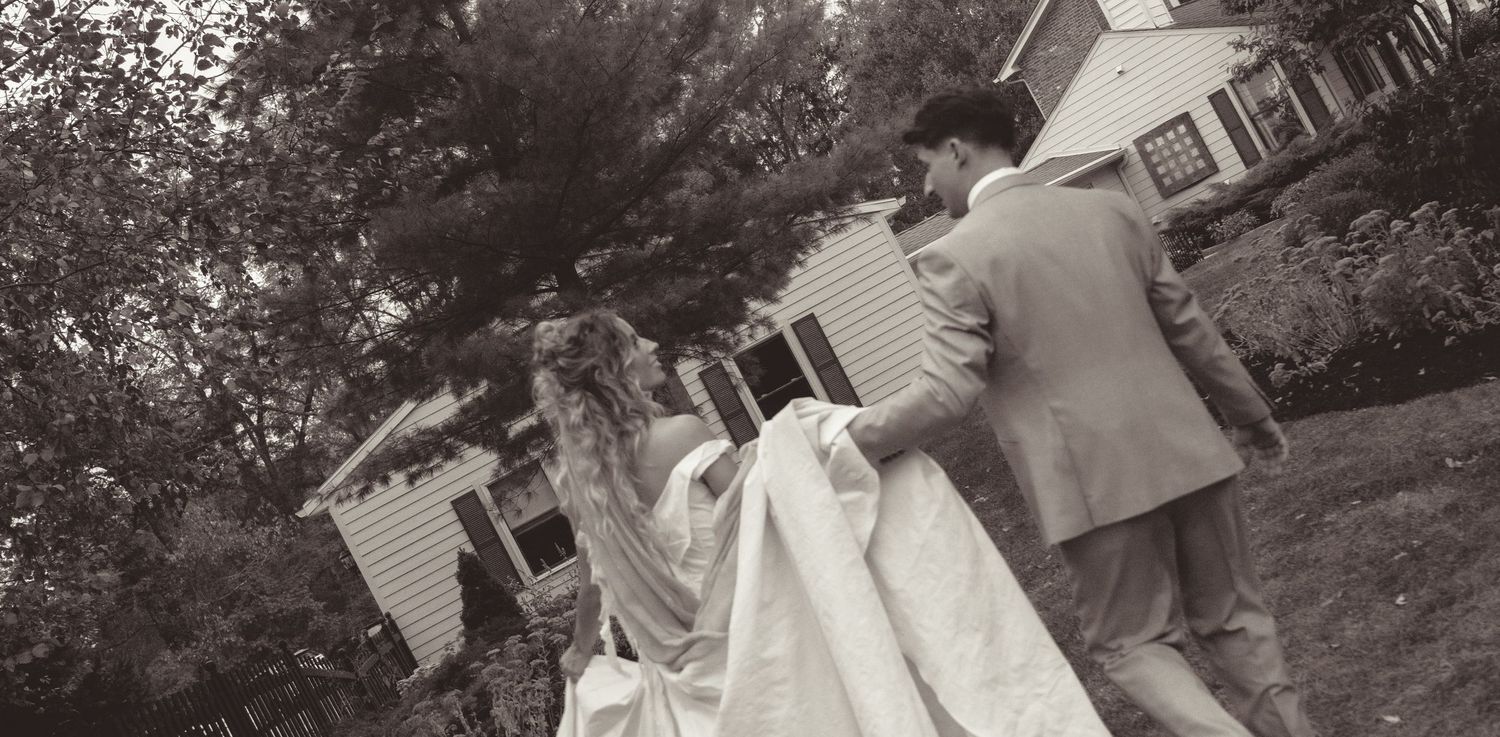 A couple shares a romantic dance moment in a garden setting with natural lighting and greenery.