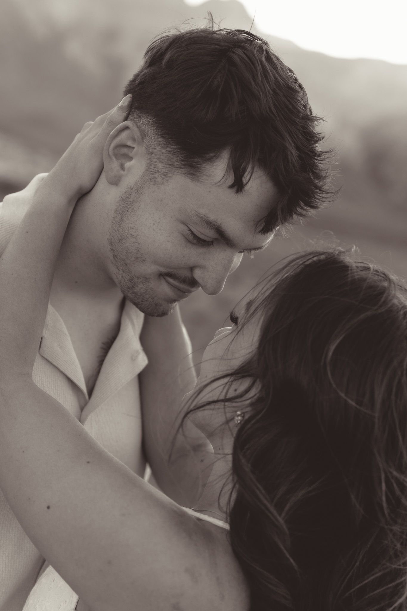 Intimate black and white close-up photo of a romantic couple embracing with eyes closed in a tender moment in the desert in las vegas, NV.