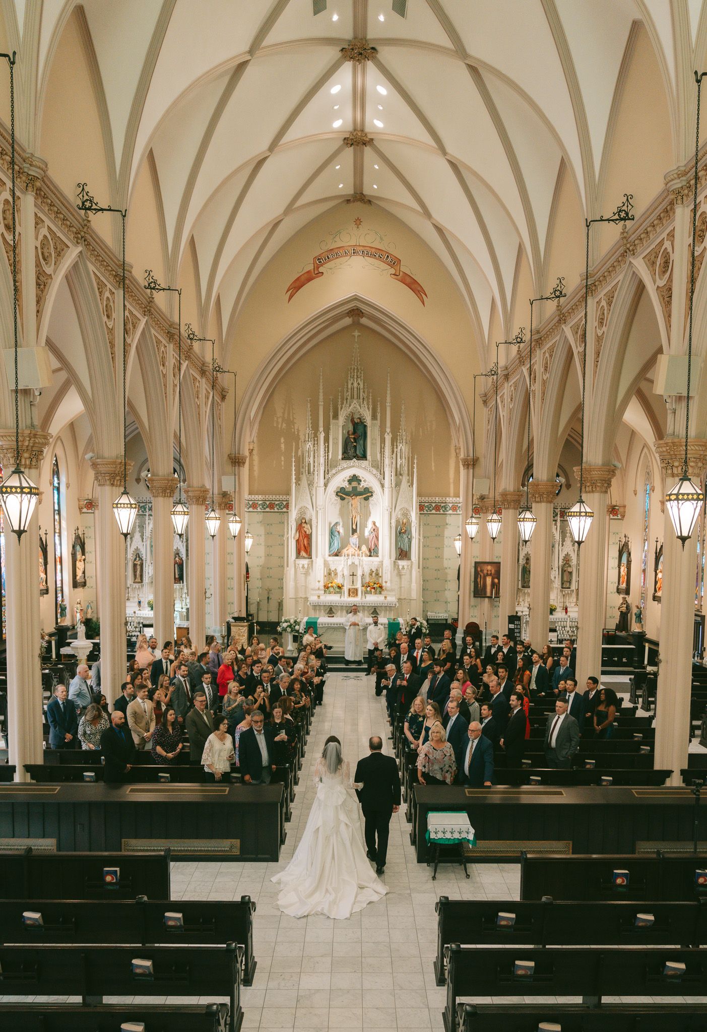 Church filled with wedding guests watching ceremony from wooden pews under vaulted ceiling in downtown pittsburgh, pa.