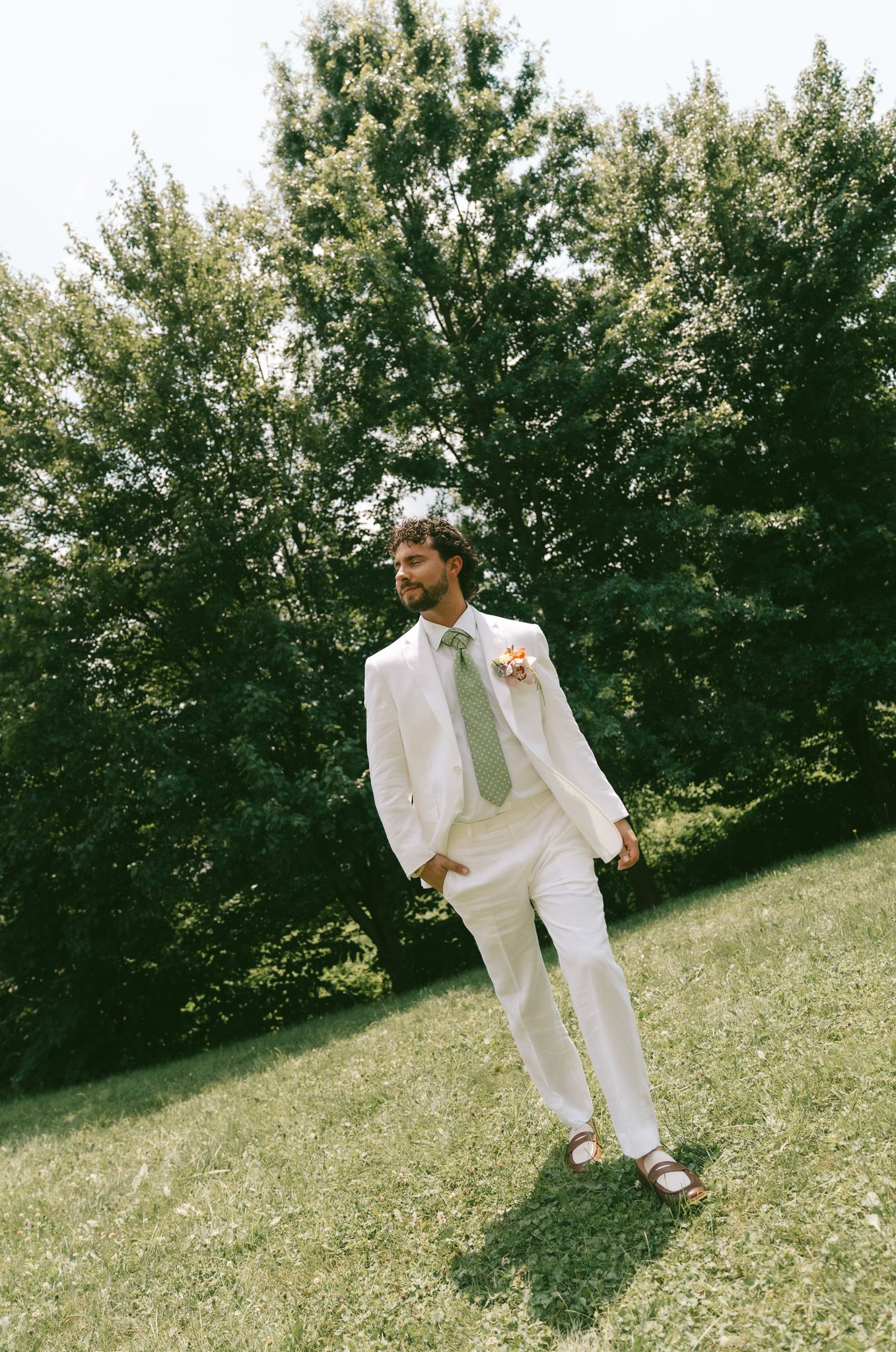 Playful dancing in white attire on a grassy hillside with trees in the background in Pittsburgh, pa.