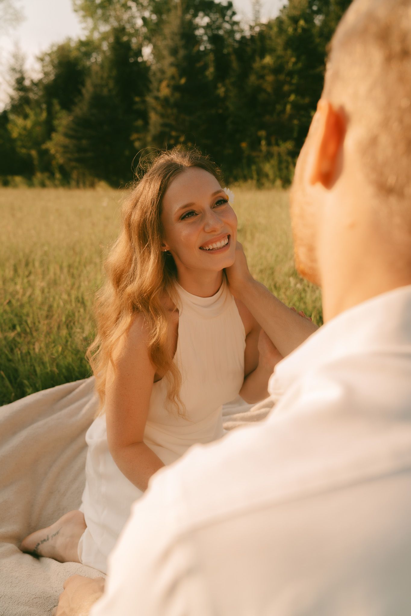 Romantic outdoor photoshoot in a sunlit field with a flowing white dress.