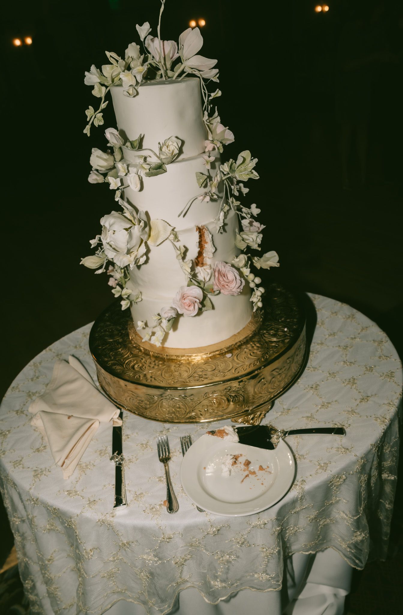 Elegant white tiered wedding cake decorated with delicate floral arrangements on a gold stand in downtown pittsburgh, pa.
