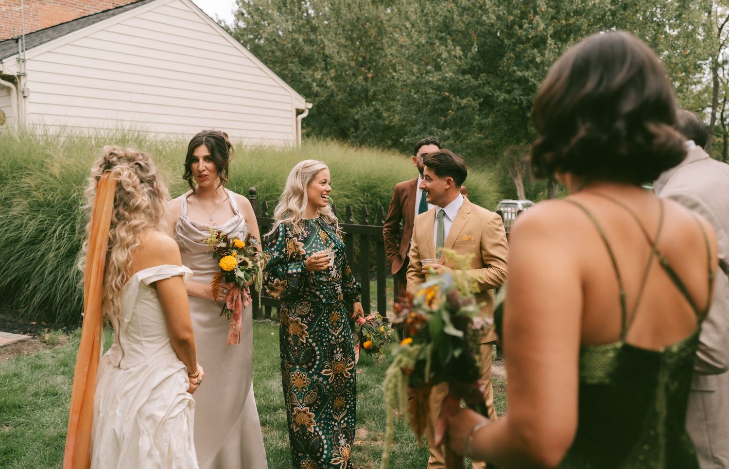 Wedding party gathered outdoors with floral arrangements and natural lighting.