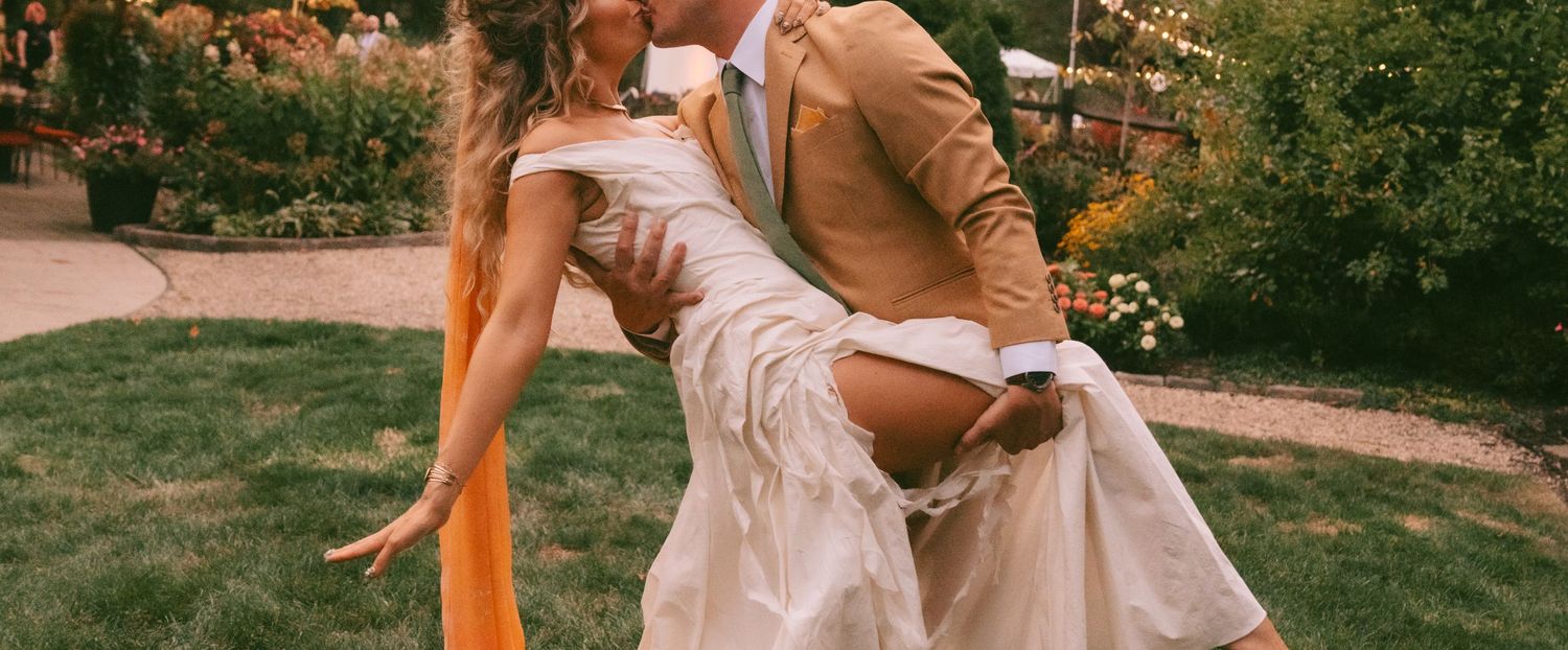 A couple poses together in a garden setting wearing coordinated outfits during a romantic photoshoot.