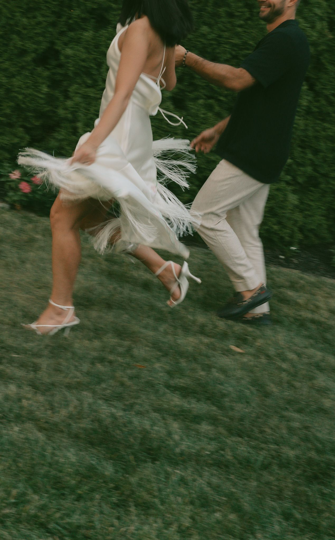 Feet and flowing white dress fabric captured in motion across green grass.