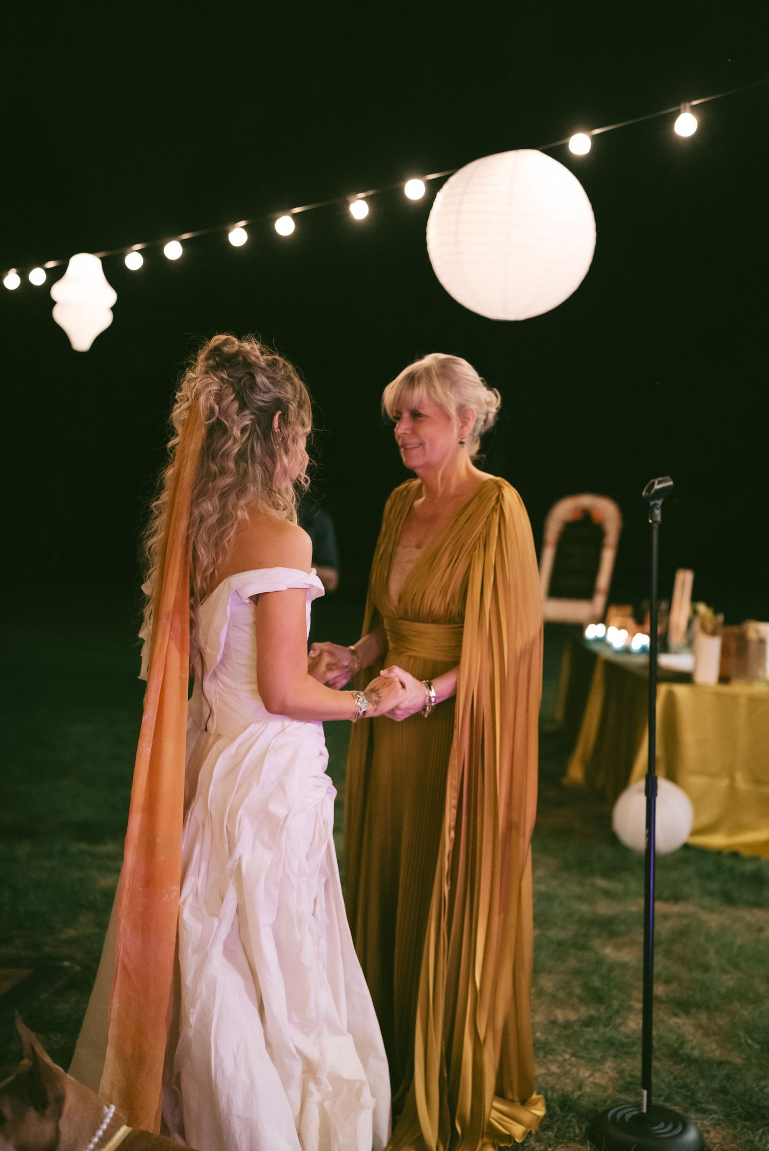 Evening outdoor wedding reception with string lights and paper lanterns creating ambient atmosphere.