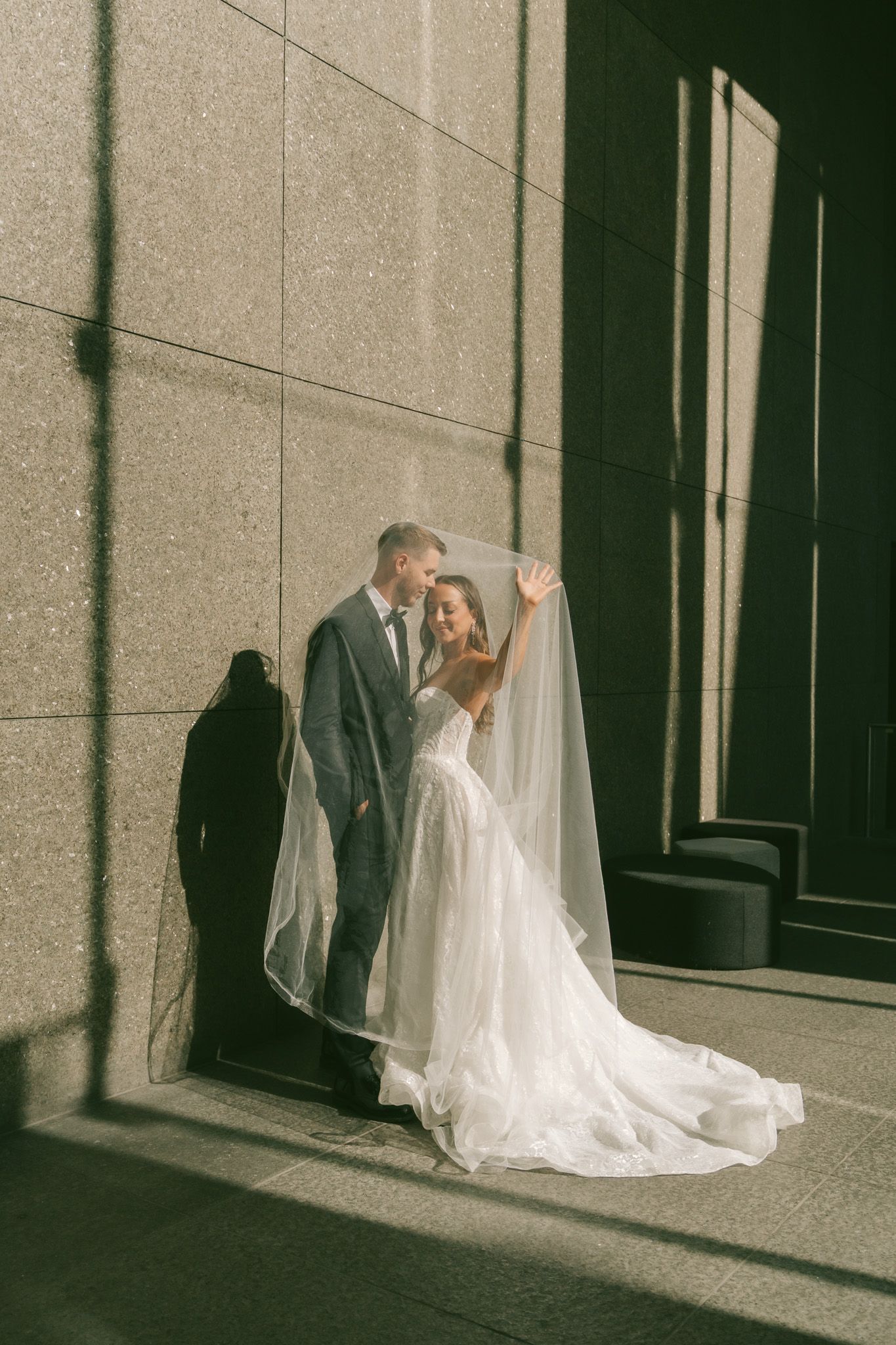 A bride in white gown and groom in dark suit share intimate moments in a series of architectural frames.