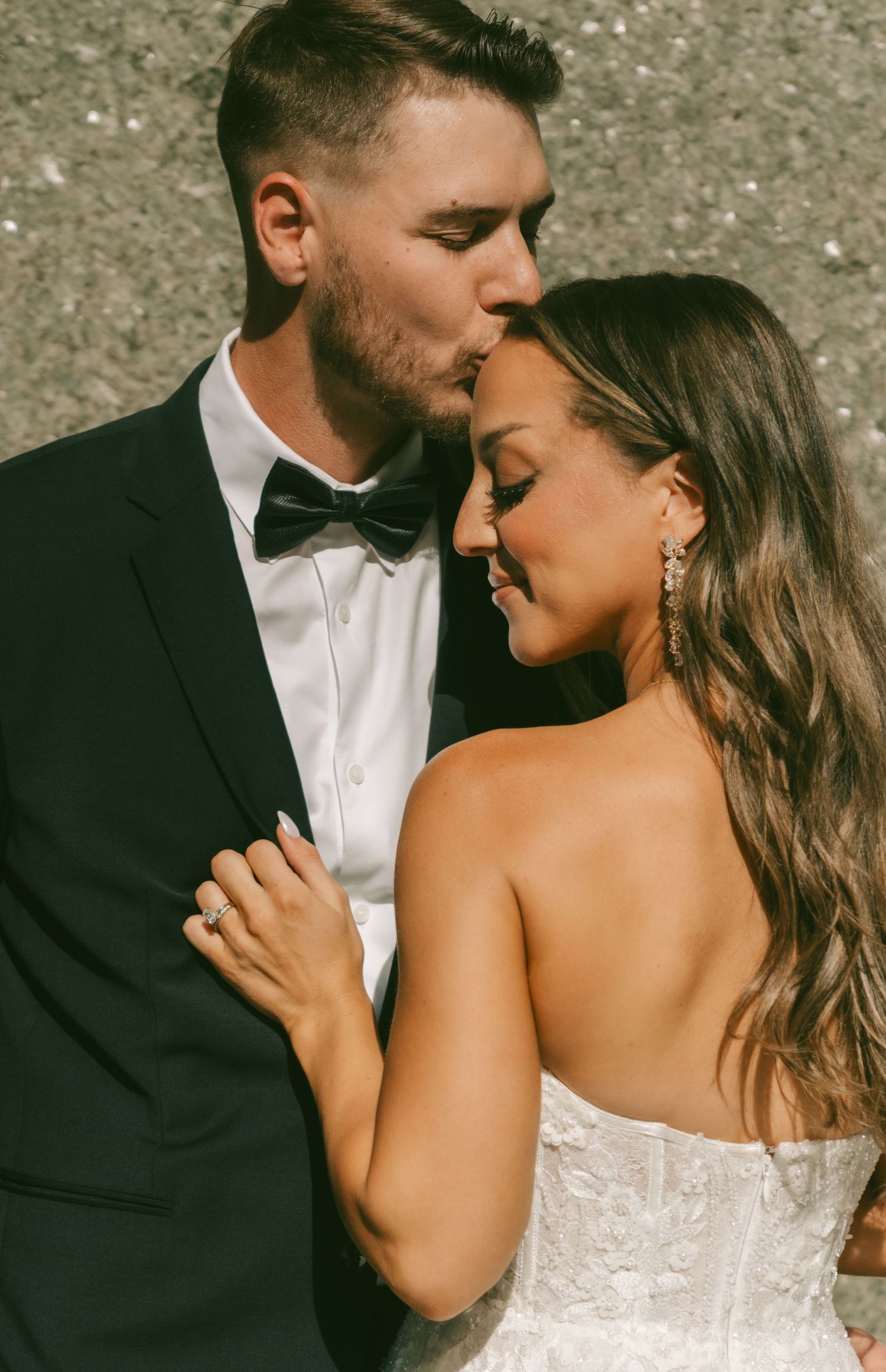Intimate wedding photo series showing a romantic moment between newlyweds in formal attire.