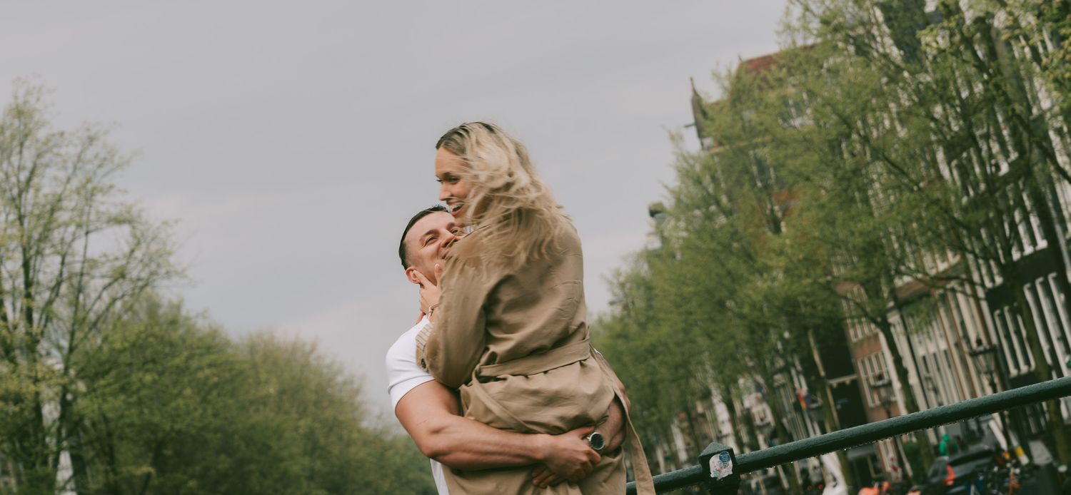 Tender moment captured against a backdrop of spring foliage in an urban setting in Amsterdam.