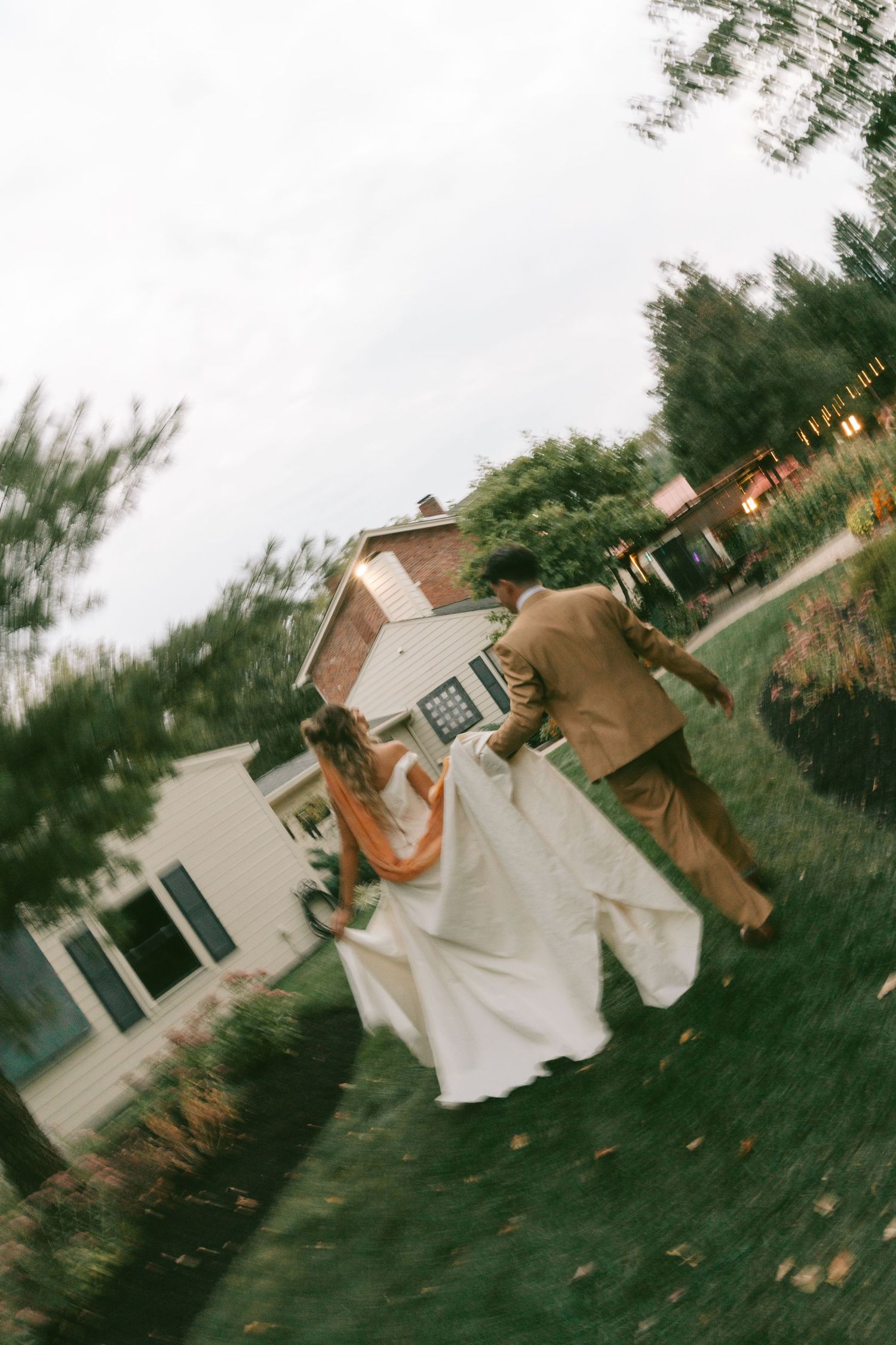 A sequence of four action shots showing a person doing a backflip on grass in front of a house at sunset.