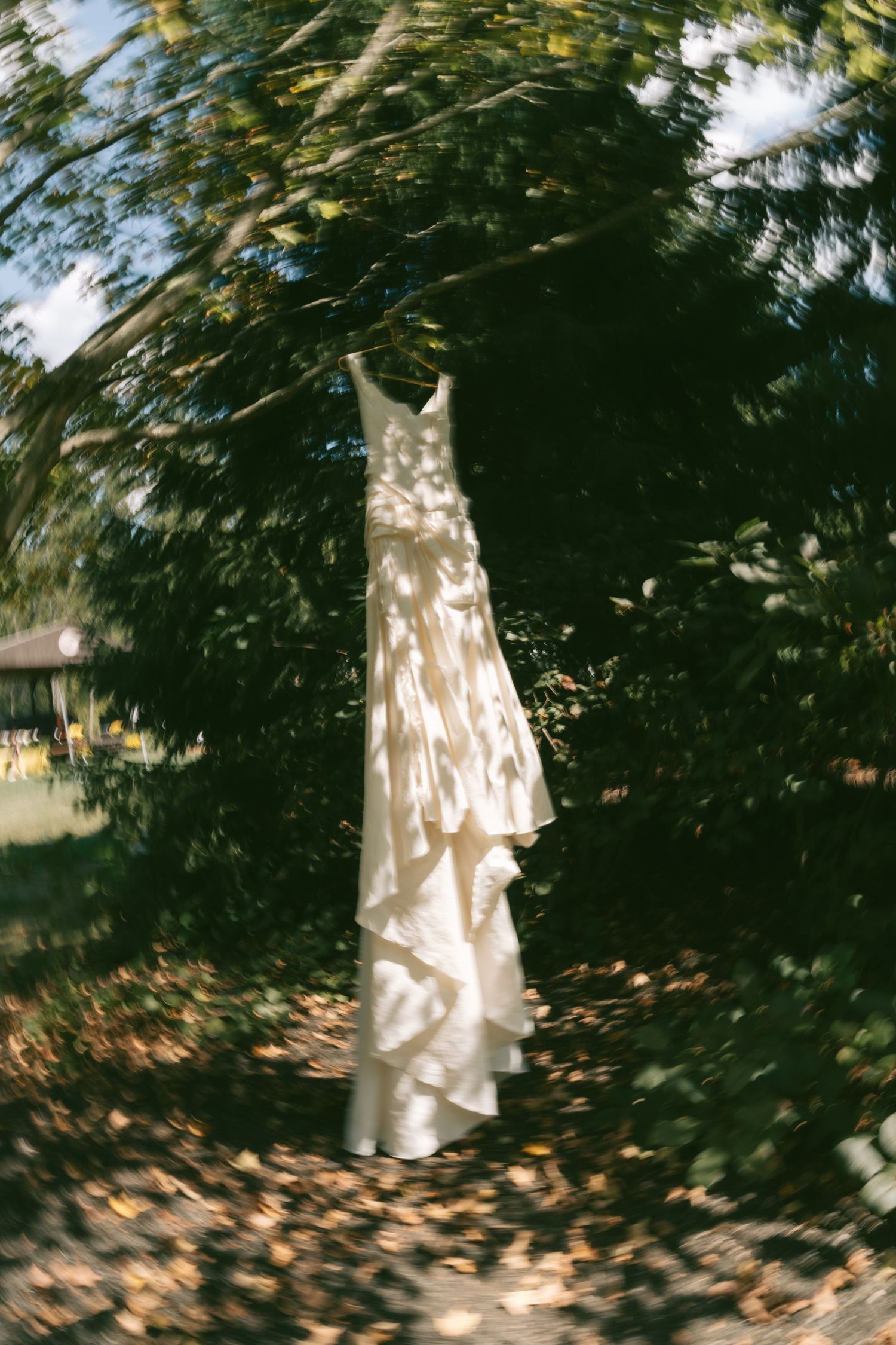 White dress hanging among sun-dappled trees in a dreamy outdoor setting.