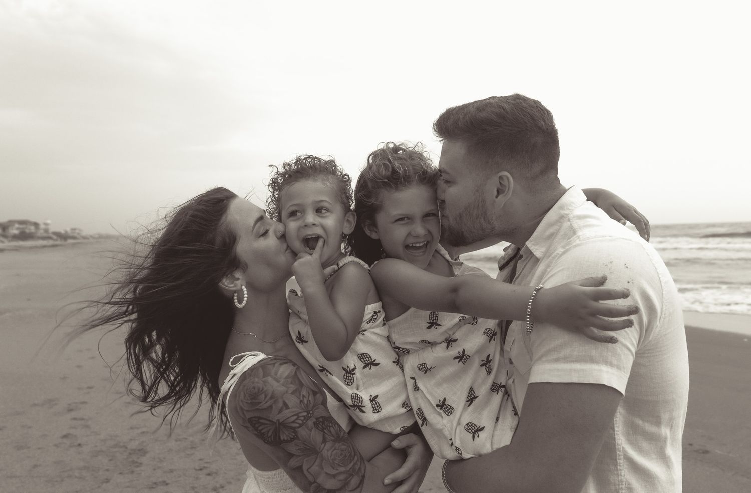 Happy family moment captured in black and white on windy beach.