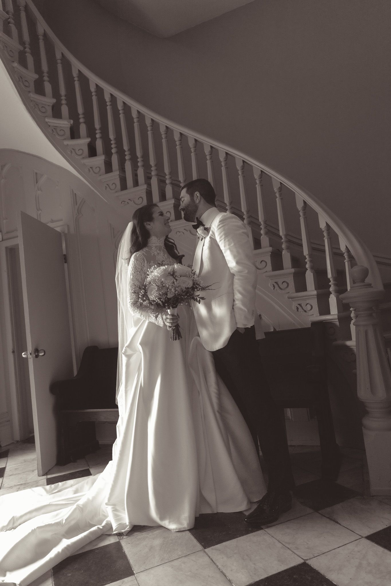 Black and white portrait of wedding couple by elegant white staircase in downtown pittsburgh, pa.