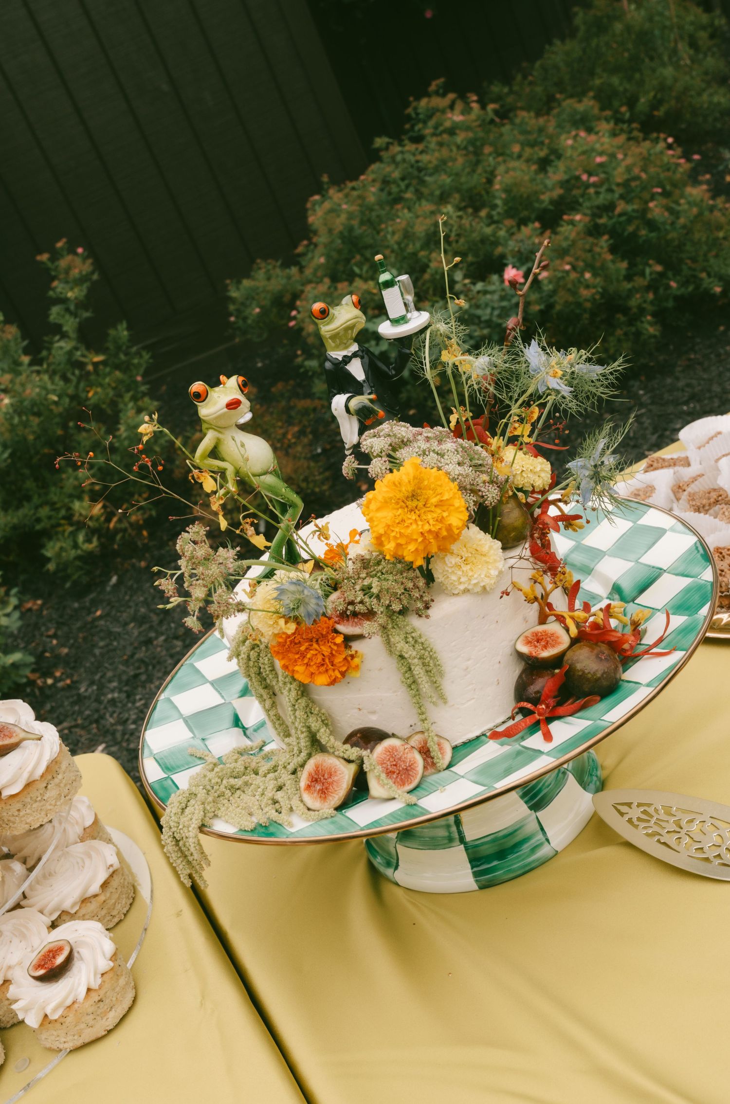Elegant wedding table settings with orange marigolds and greenery on checkered plates with decorative accents.