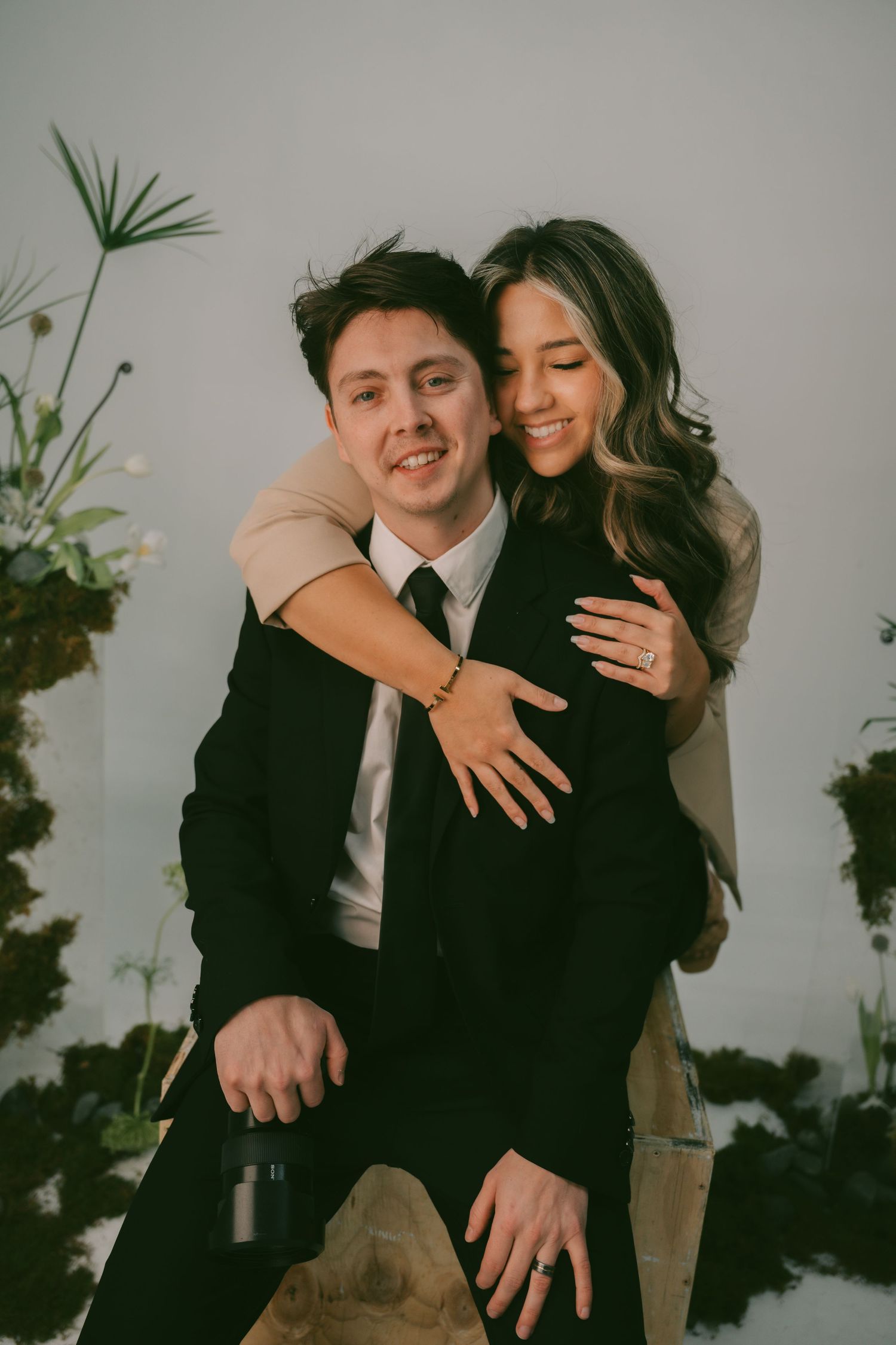A joyful embrace captured in an indoor setting with decorative plants.