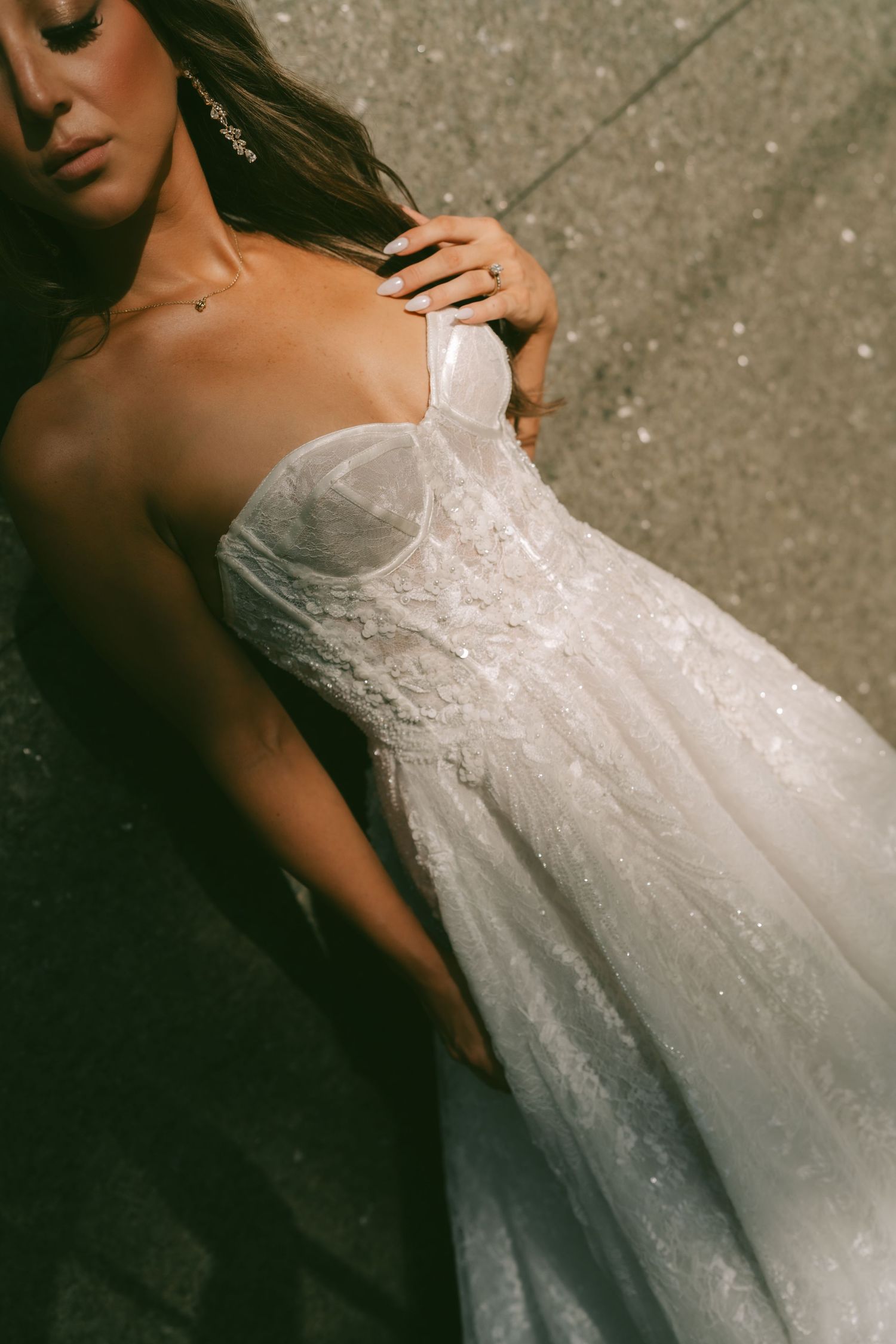 Close-up details of a white lace wedding dress with delicate beading and strapless neckline shown in multiple angles.