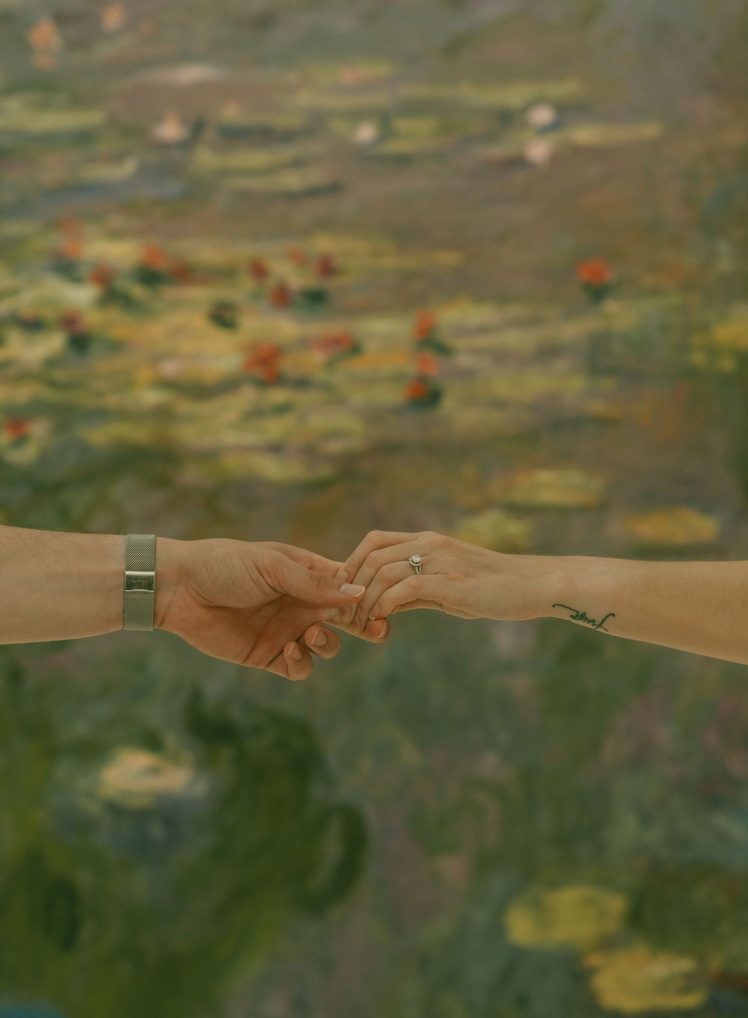 Close-up shot of hands reaching toward each other against a blurred natural background.