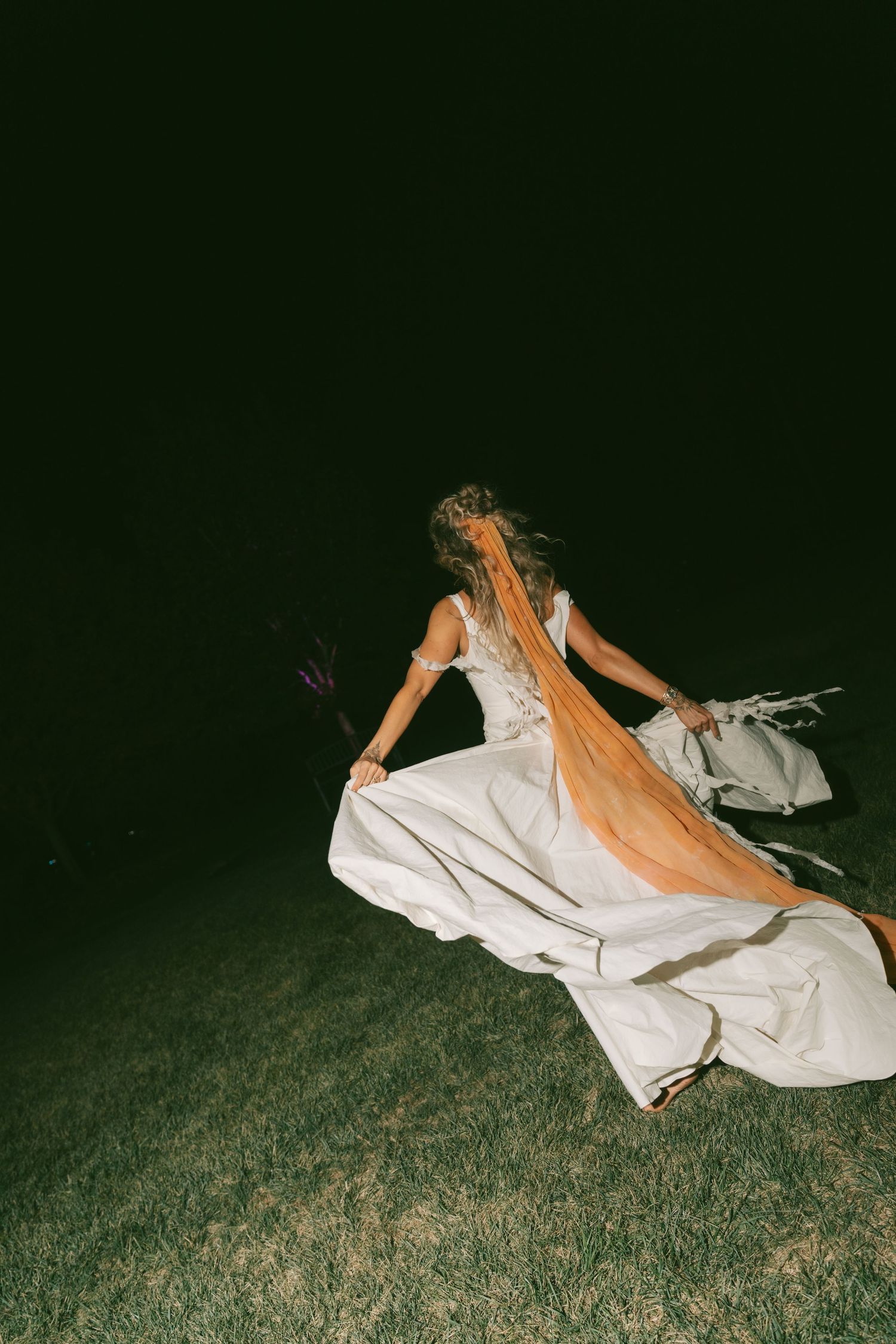 Artistic nighttime photos showing movement across grass in flowing white fabric.