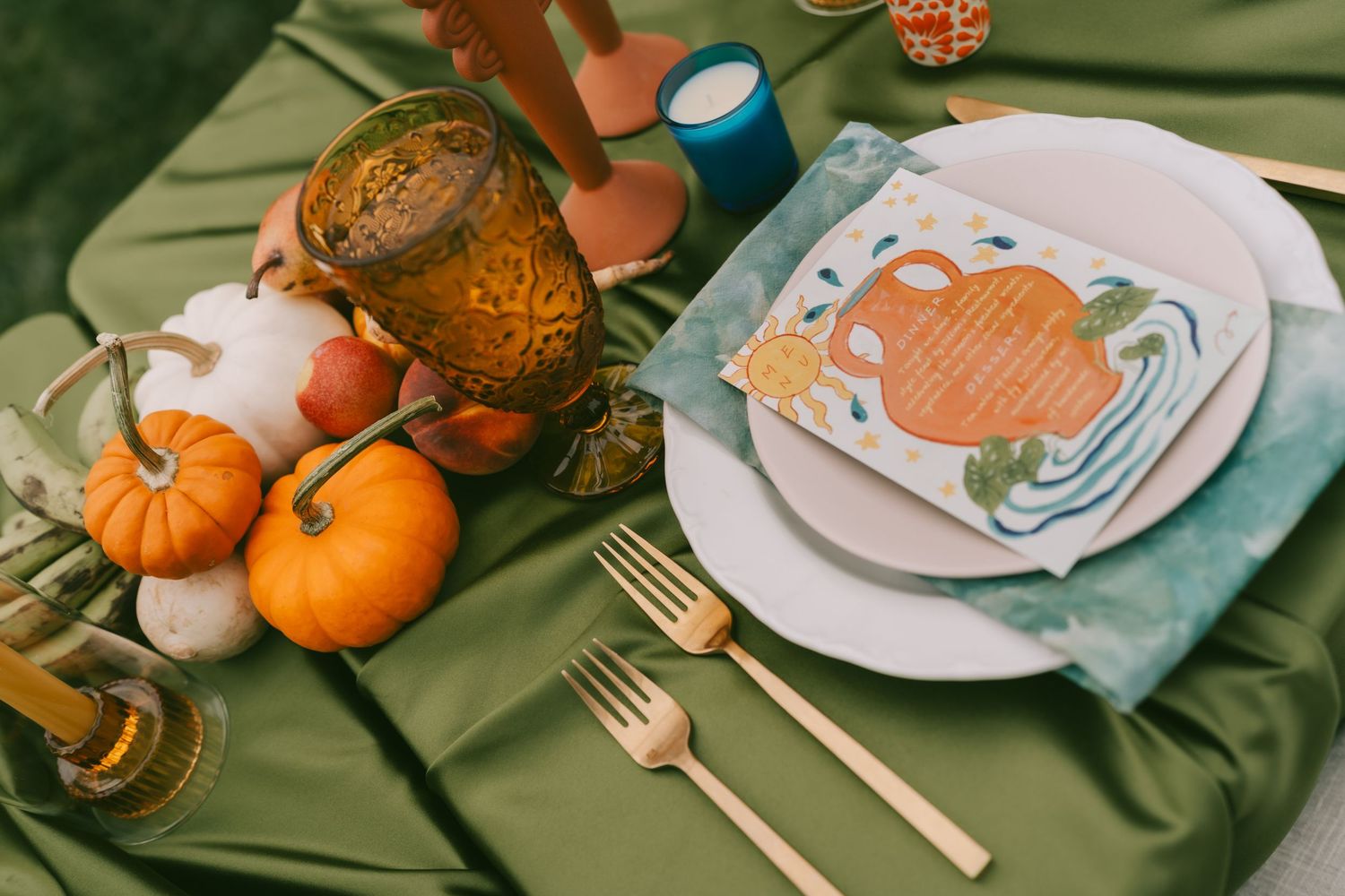 Fall-themed wedding table settings with pumpkins, gold flatware, and teal napkins.