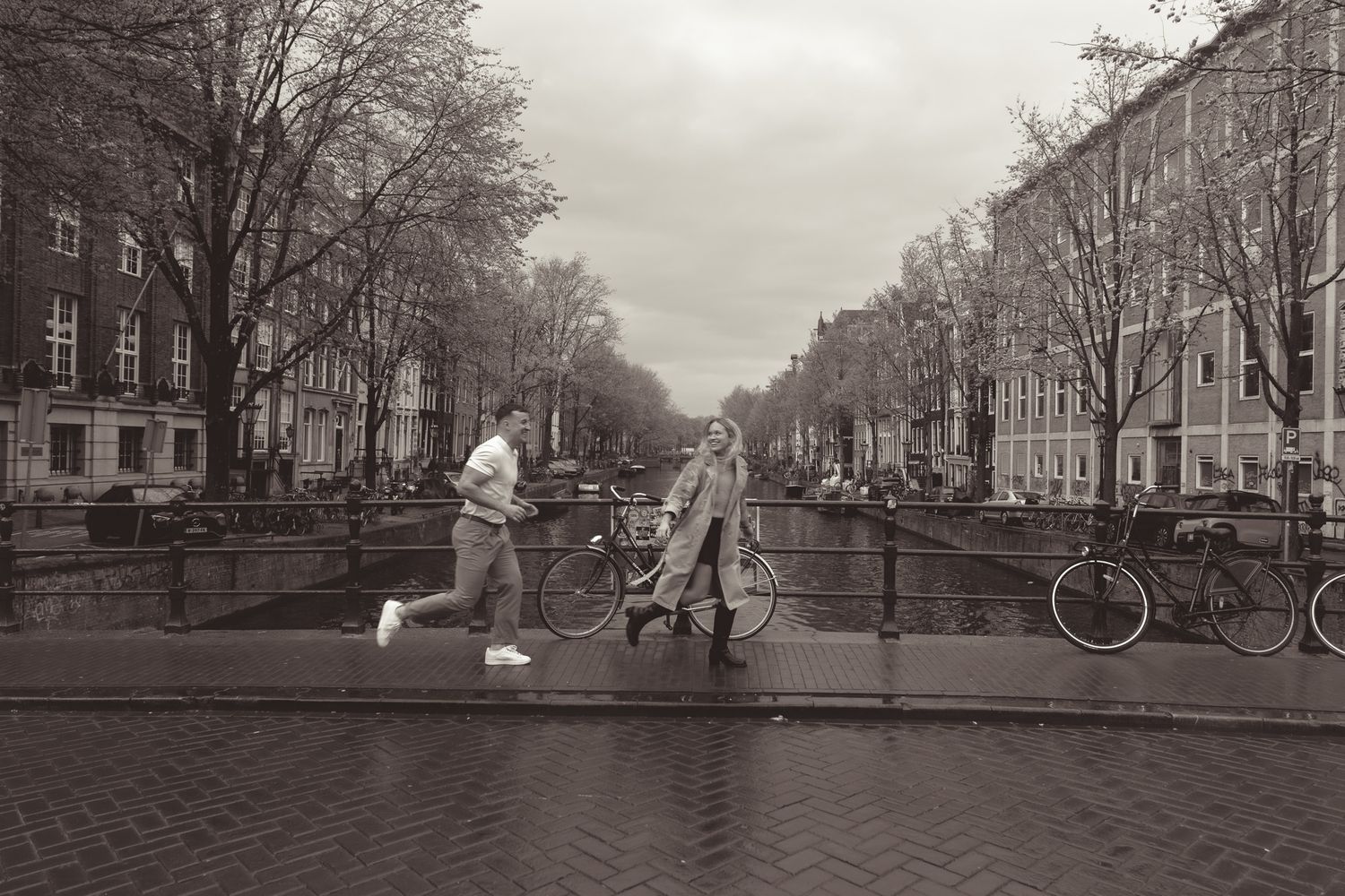 Romantic couple photoshoot along a charming cobblestone street in Amsterdam with bicycles and historic buildings.