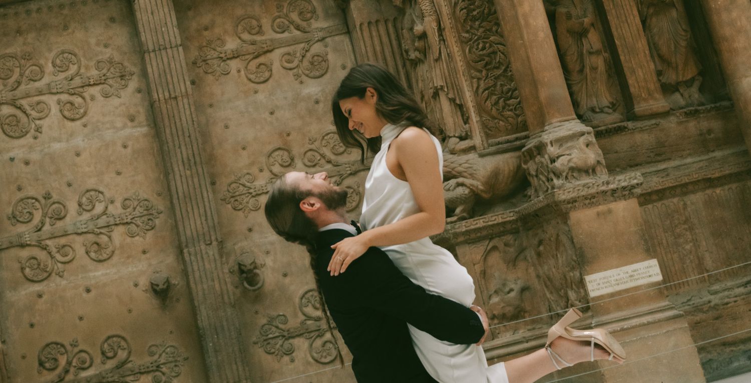 Wedding couple poses beside rustic stone walls and ornate columns in romantic photo series in Carnegie Museum of art in pittsburgh