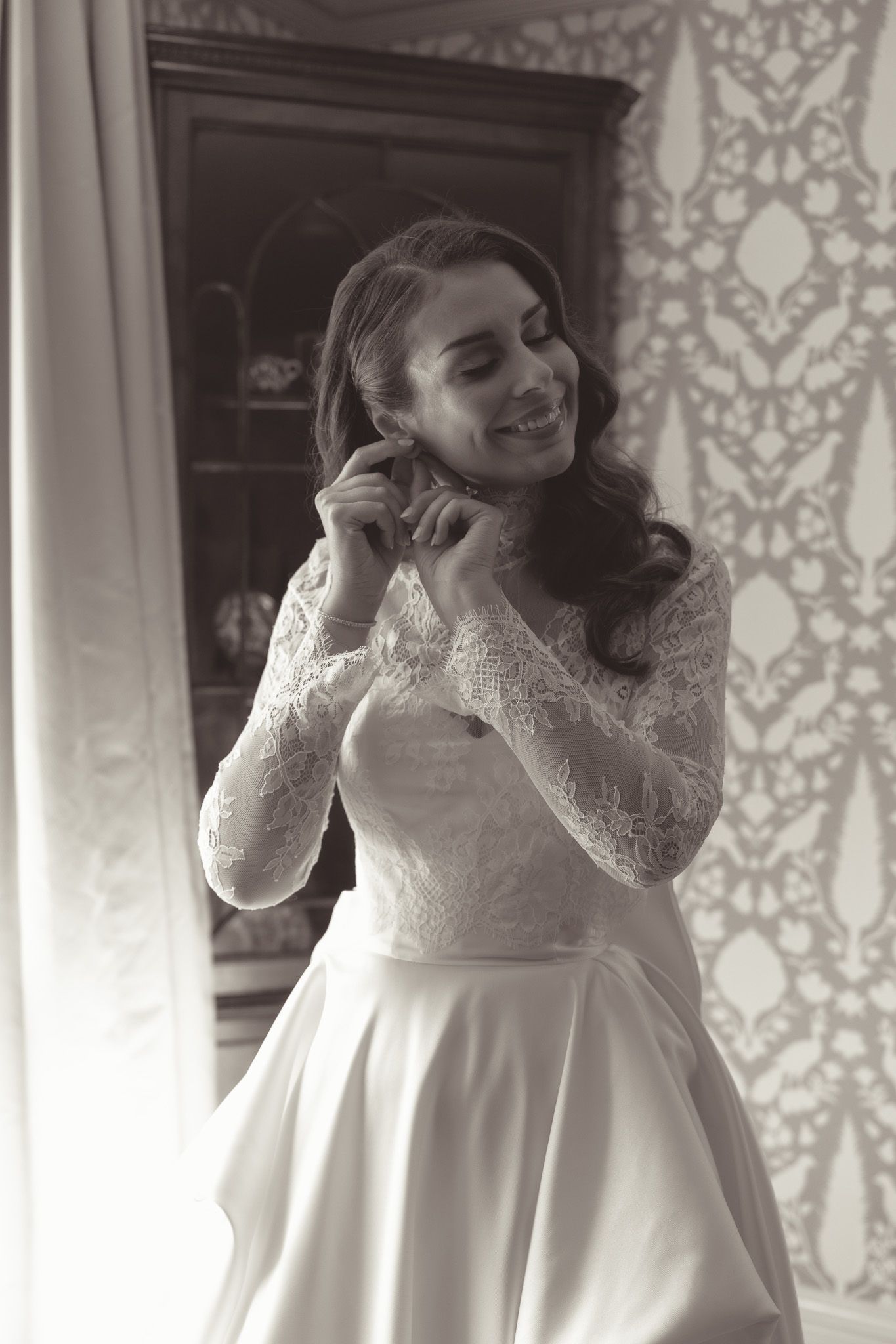Bride in long-sleeve lace wedding dress laughs joyfully during getting ready moments in downtown pittsburgh, pa.