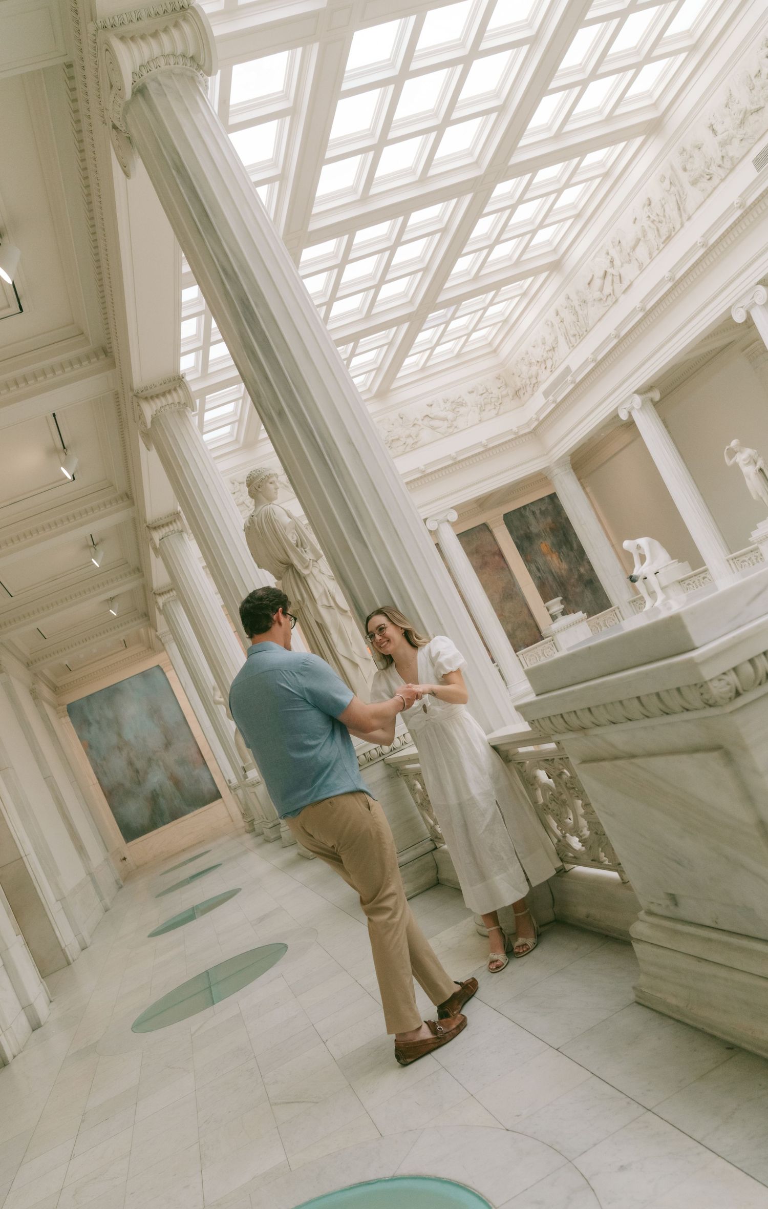 Museum interior with white marble columns and natural lighting from above.