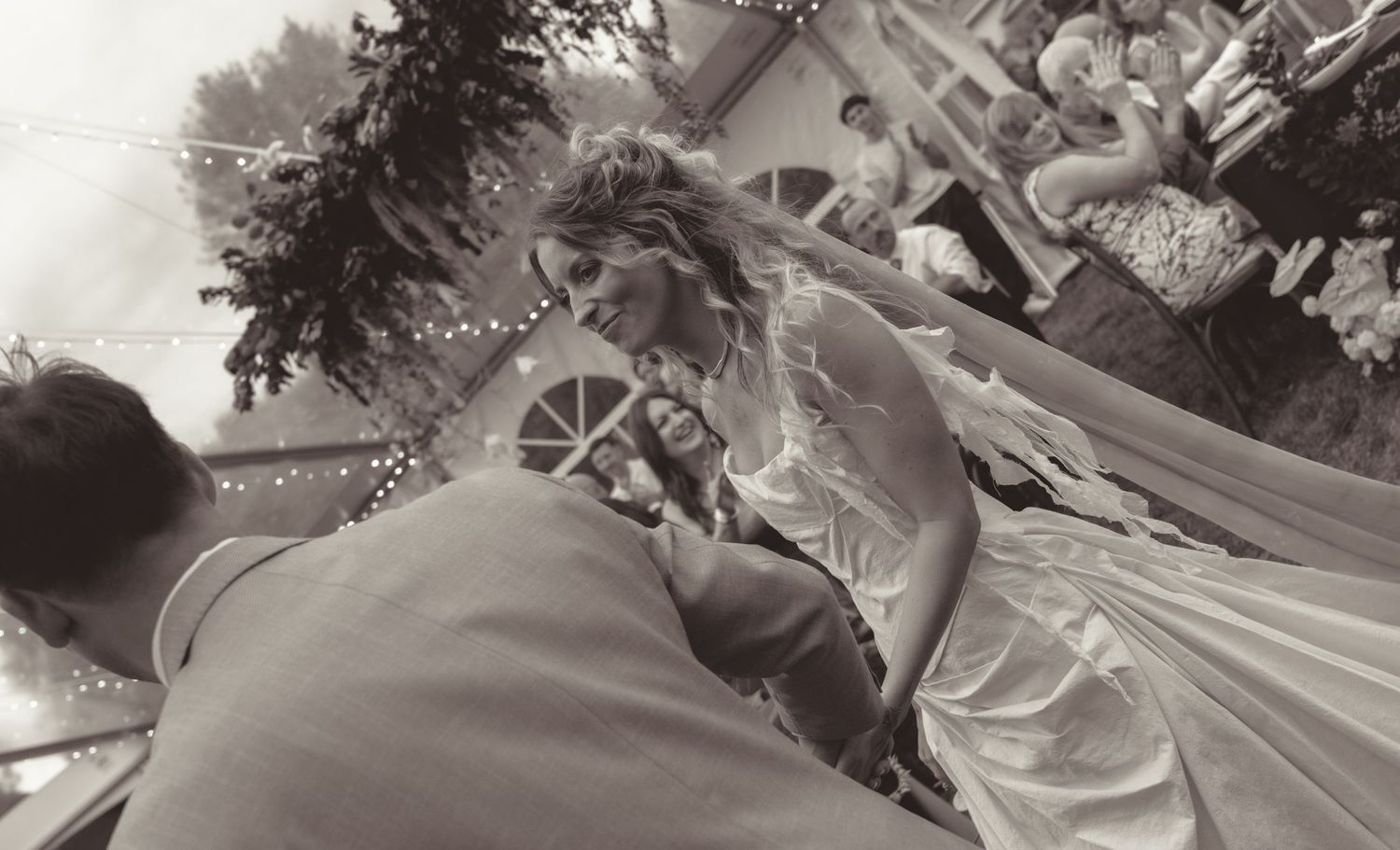 Black and white wedding photo showing a couple's first dance outdoors.