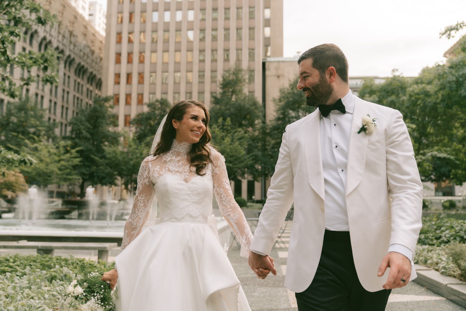 Newlyweds share a romantic moment walking together in an urban garden setting in downtown pittsburgh, pa.