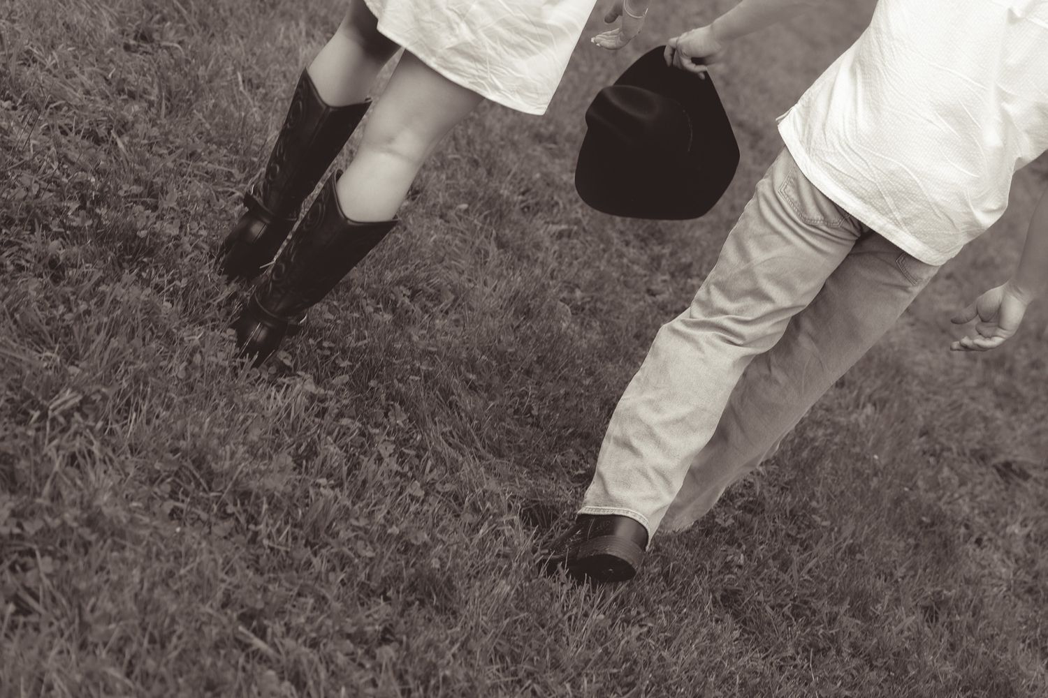 Black and white detail shot of feet walking on grass.