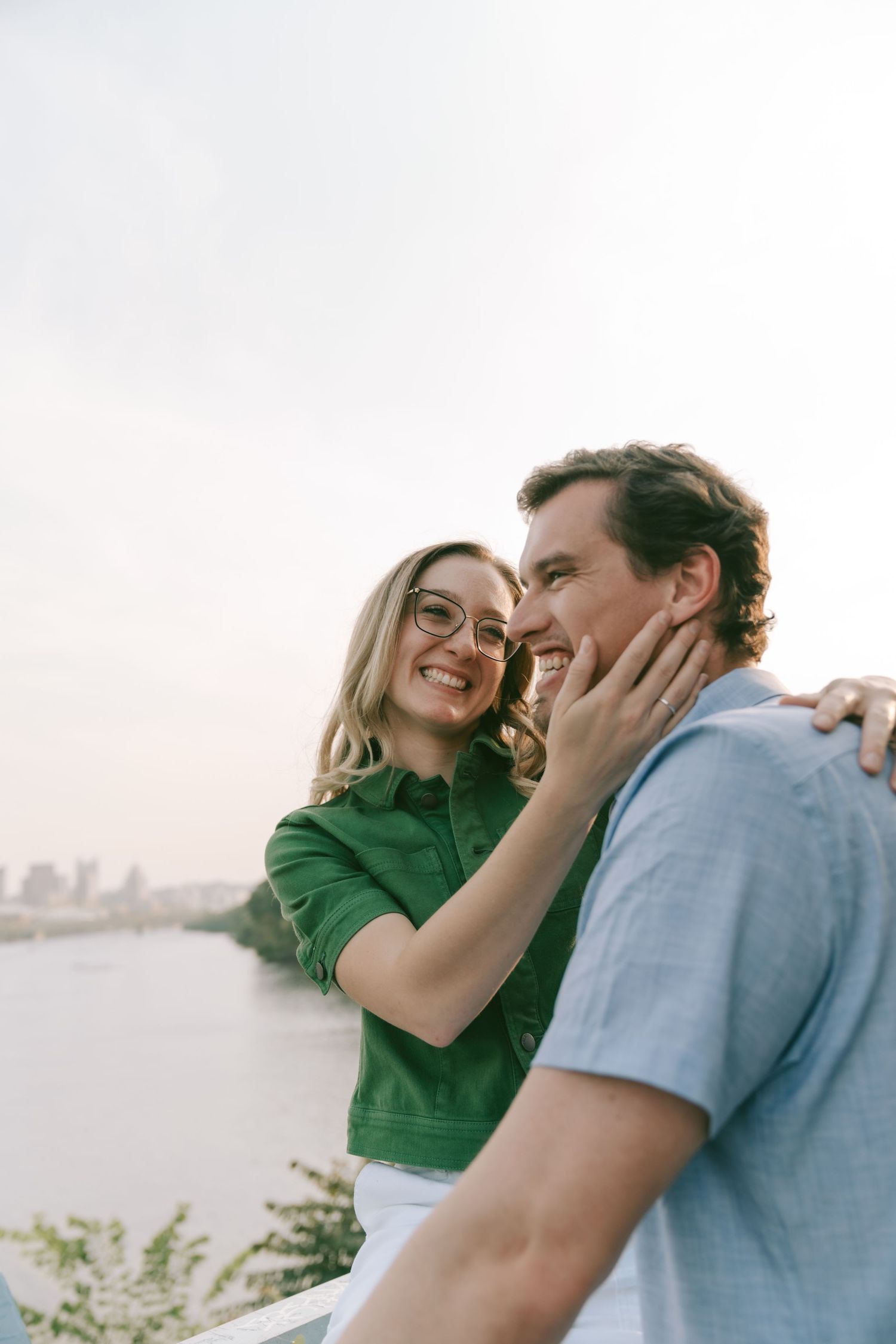 A couple sharing a tender moment against a cityscape background at sunset.