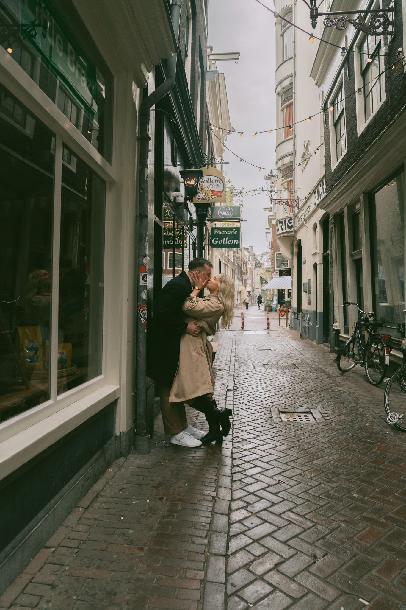 Romantic encounter on a narrow cobblestone street lined with historic buildings in Amsterdam.