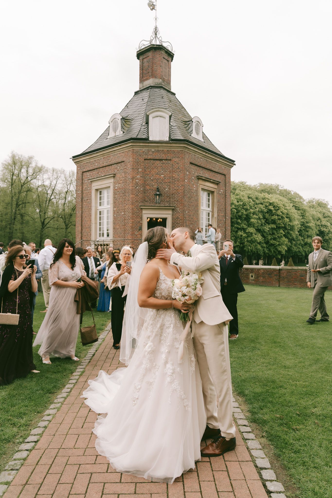 Elegant wedding ceremony takes place outside a historic brick chapel with octagonal architecture in Germany.