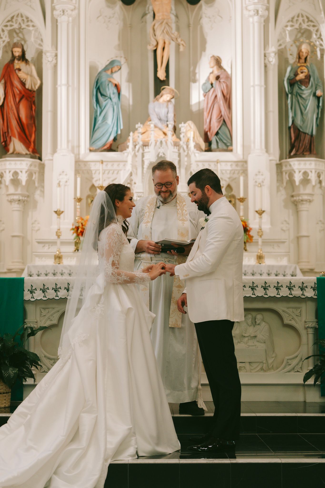 Traditional Catholic wedding ceremony taking place at an ornate church altar with religious statues in downtown pittsburgh, pa.