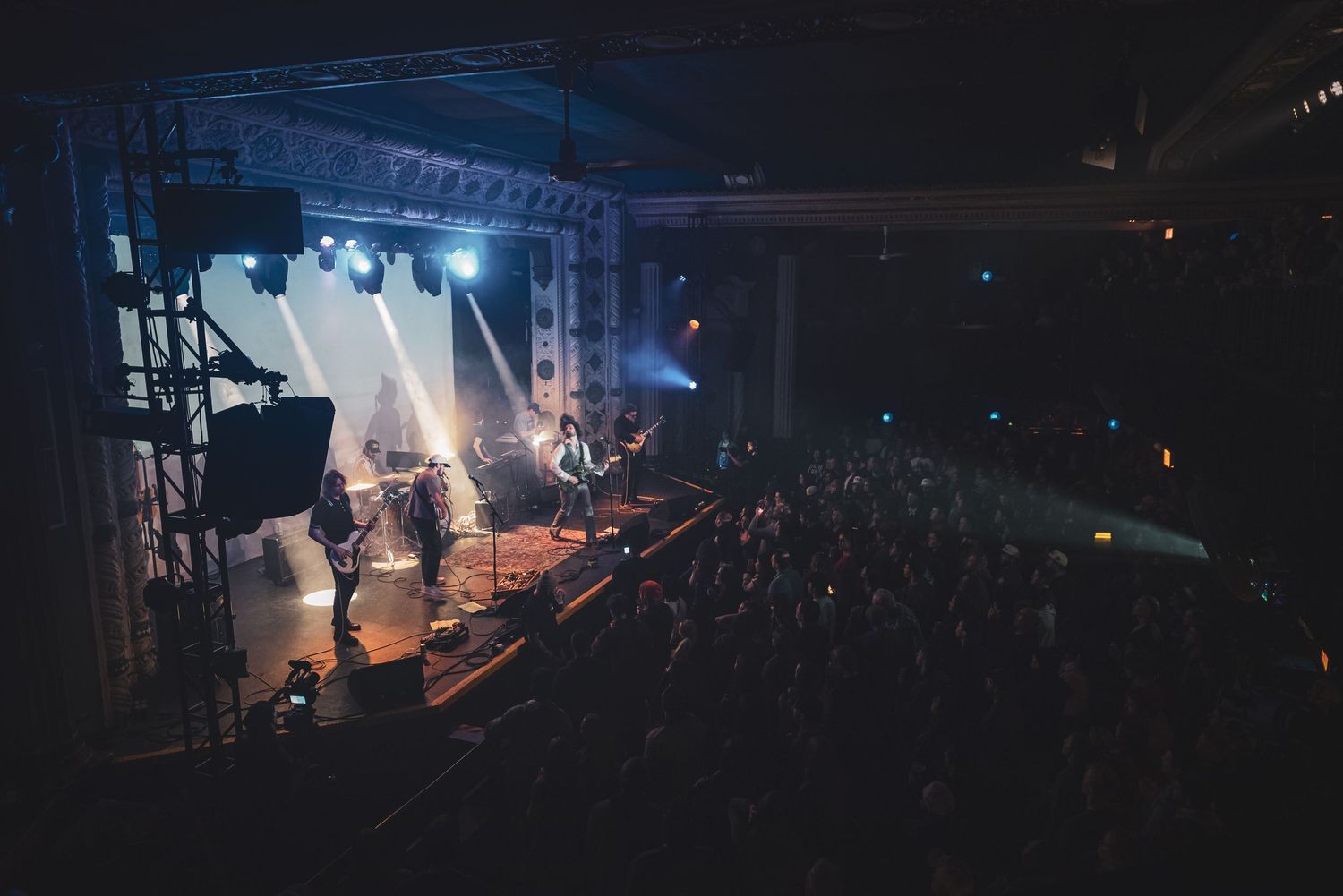 Dark concert stage with atmospheric lighting and fog effects during a live music performance.