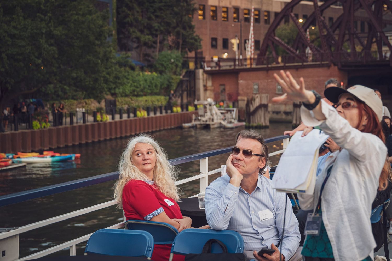 Group enjoying a boat tour on a river with city buildings and bridges in the background.