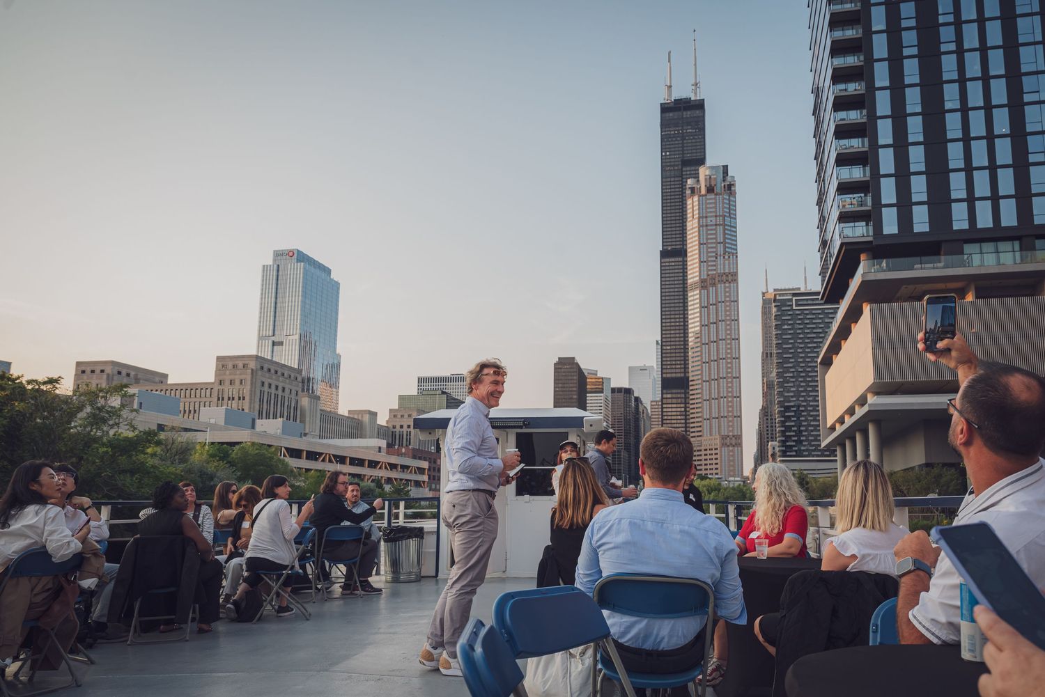 People gathered at rooftop venue with Chicago skyline visible in background at dusk. goose.img photography LLC - Chicago Photographer
