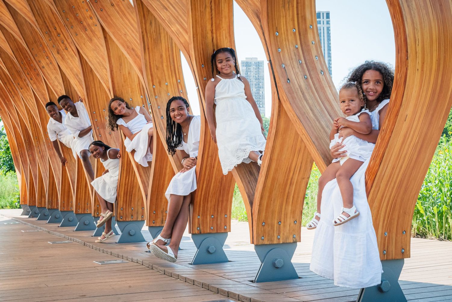 A creative portrait of people in white dresses posing within curved wooden architectural elements.
