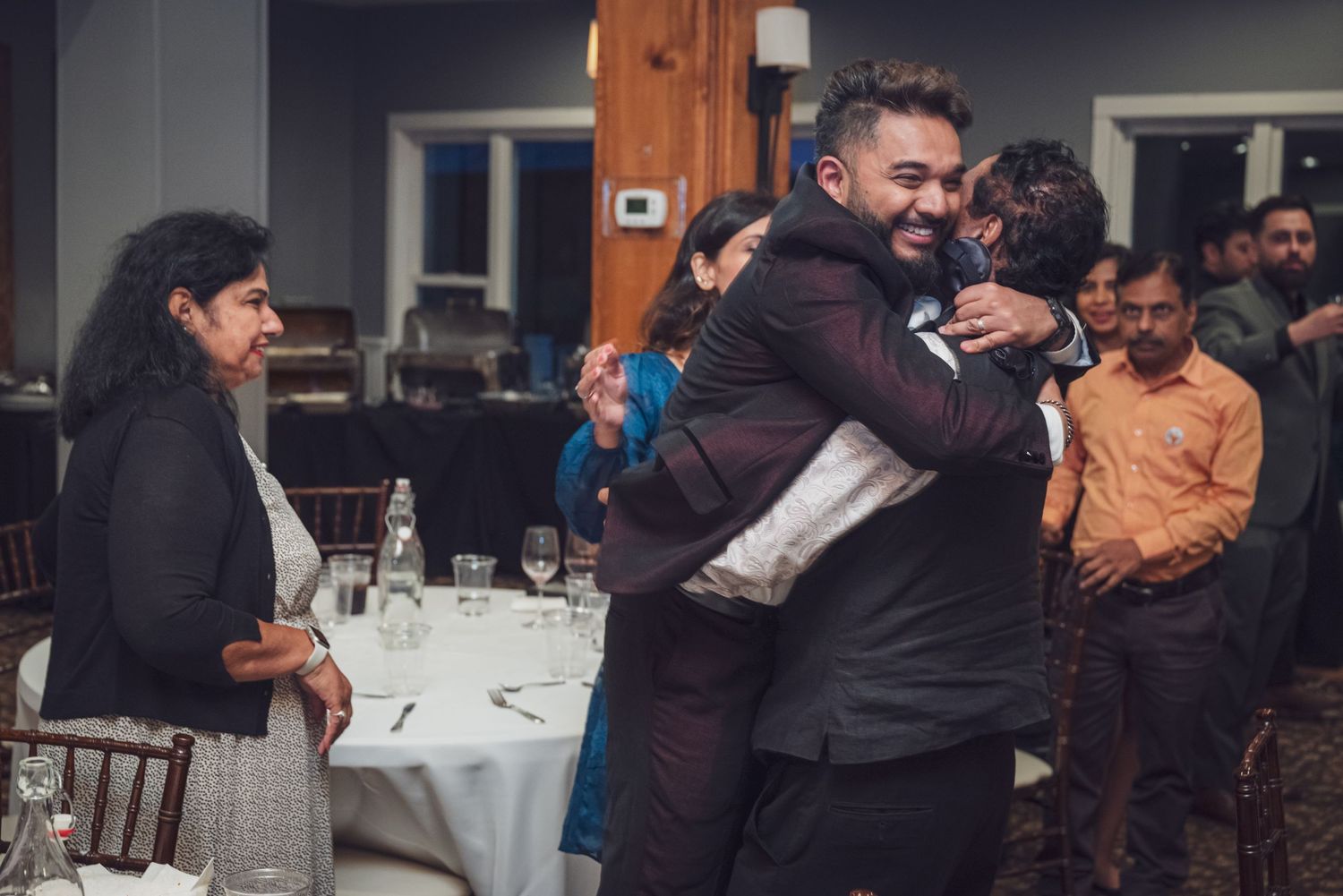 People sharing an emotional embrace at what appears to be a formal dinner event.