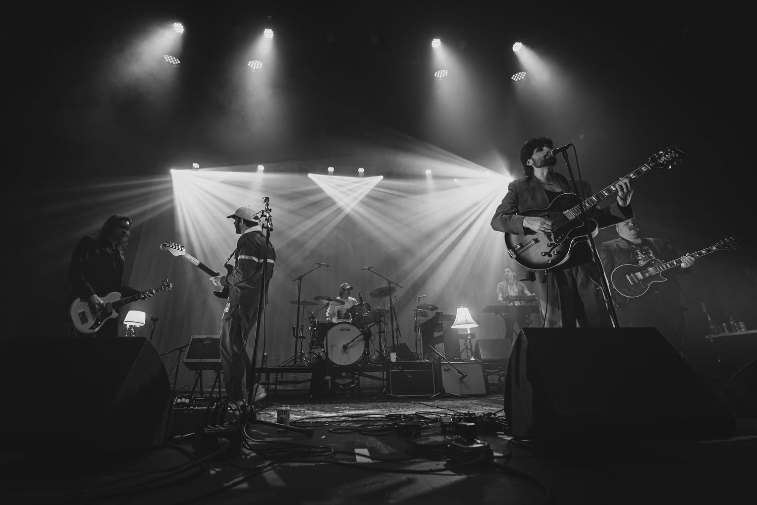 Black and white concert photos show performers on stage under dramatic spotlights during a live music performance.